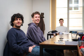Three young men sitting at a table indoors.