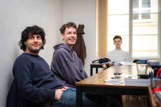 Three young men sitting at a table indoors.