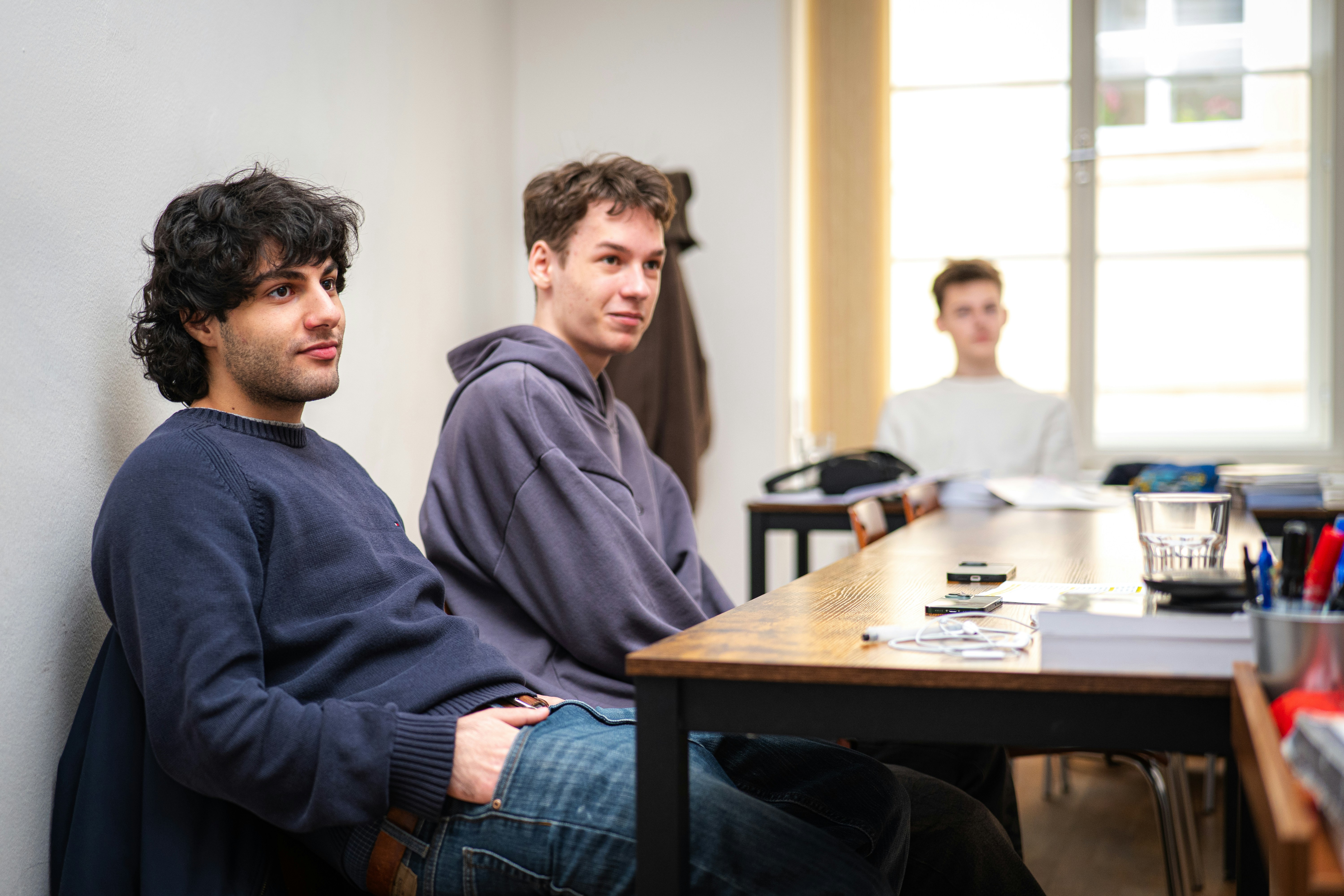 Three young men sitting at a table indoors.