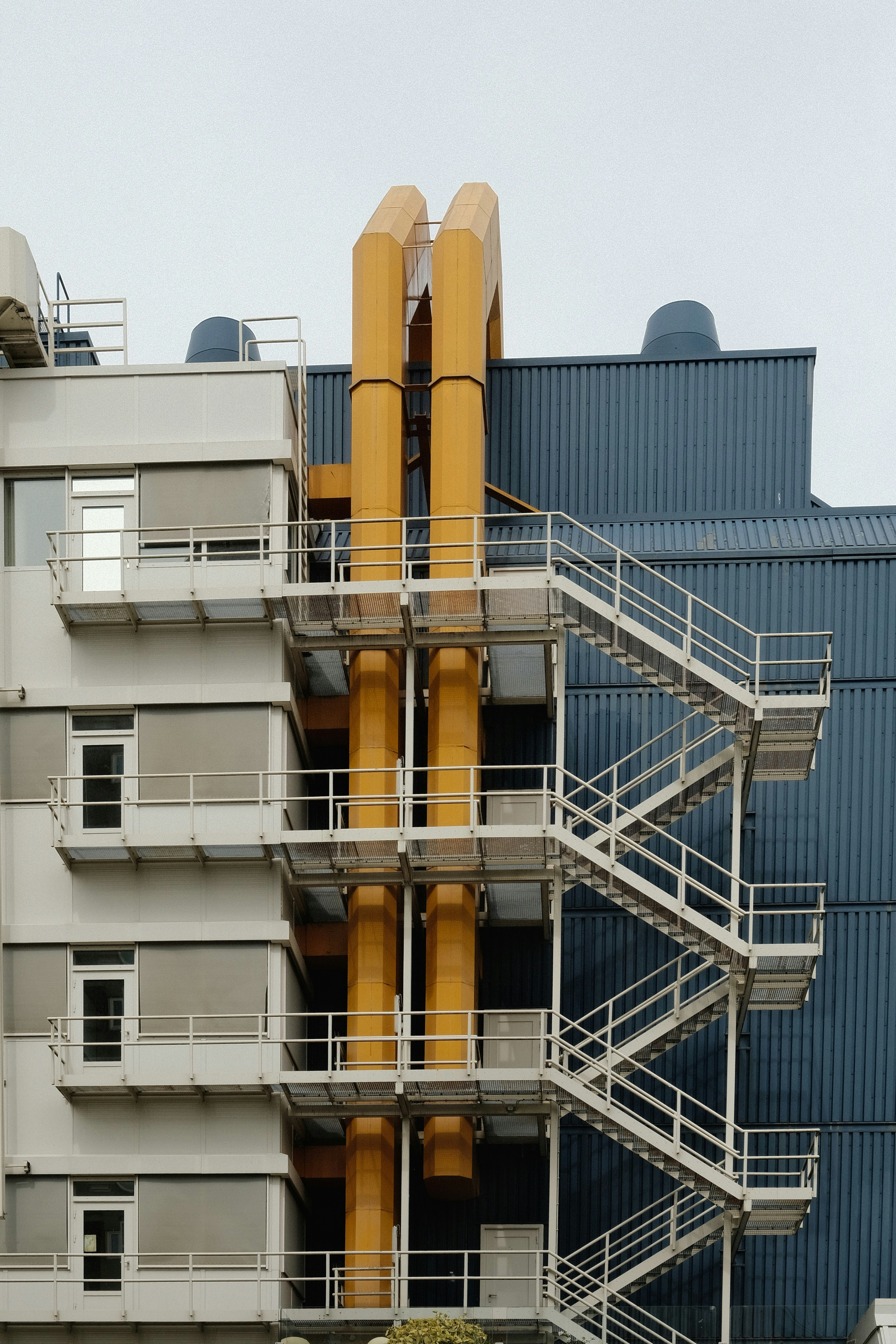 Modern building exterior with yellow pipes and stairs