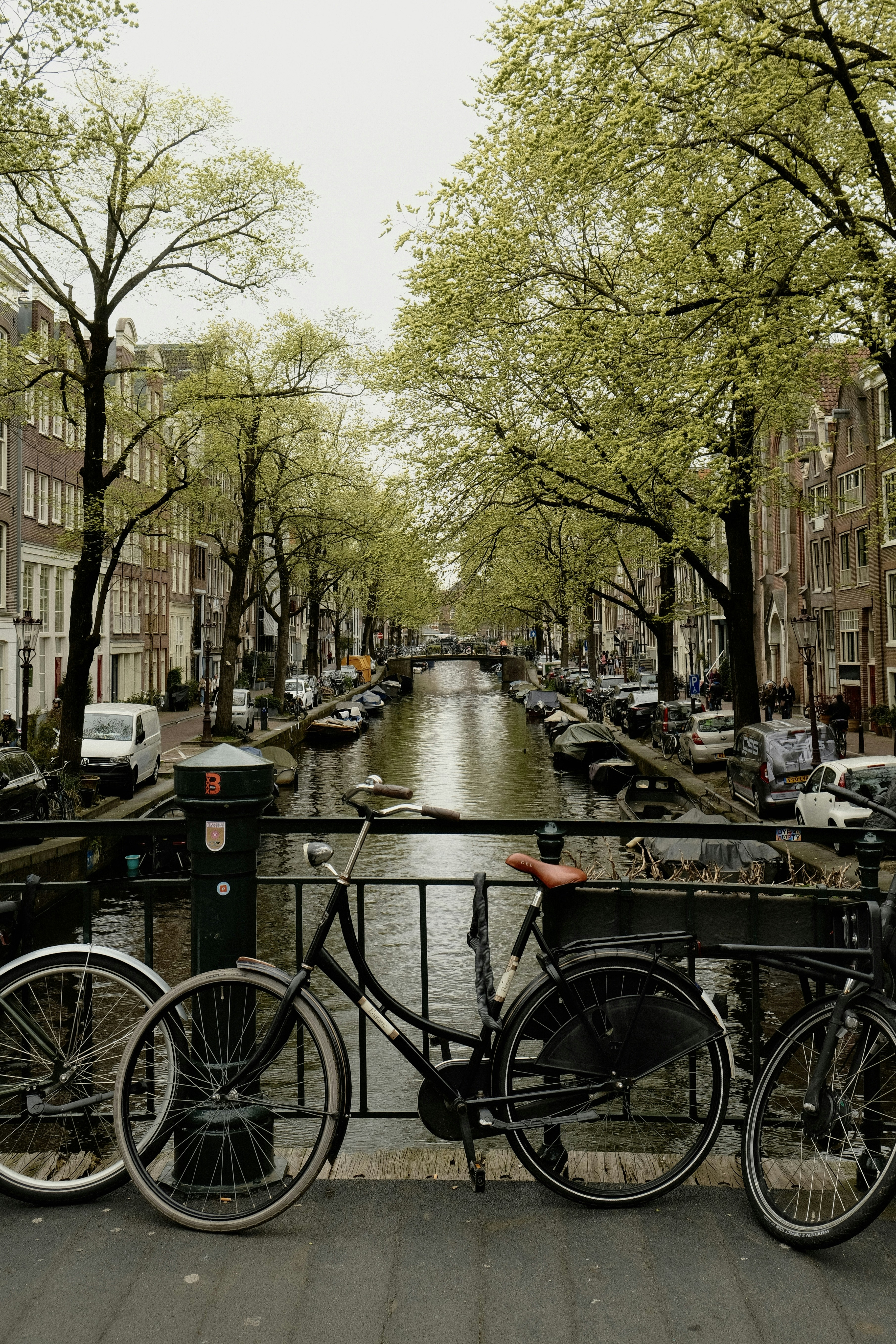 Bicycles parked on a bridge over a canal in amsterdam.