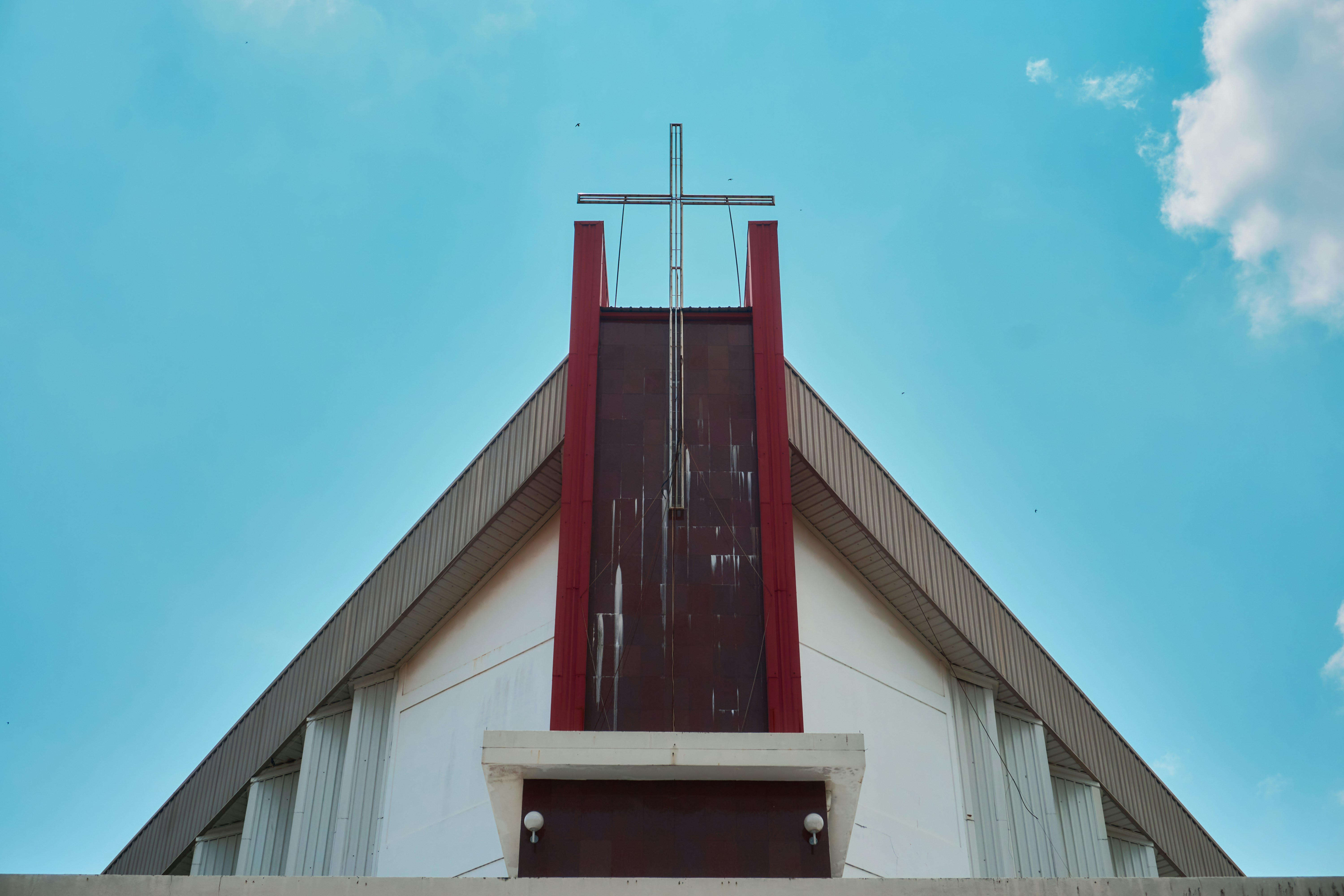Fachada moderna da igreja com cruz contra céu azul