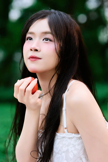 Young woman holding a strawberry outdoors