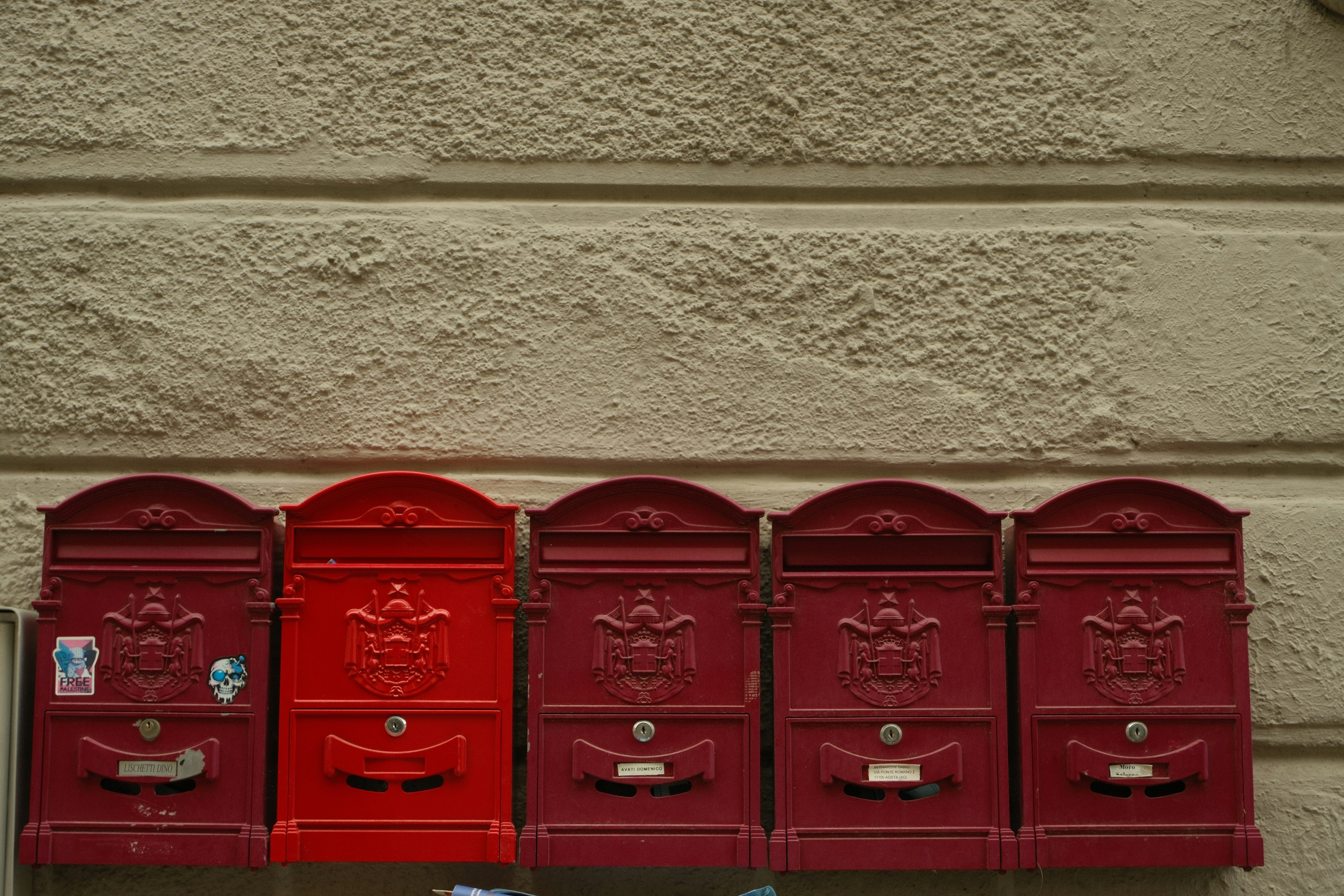 Five red mailboxes with one distinct red mailbox. (Photo by sorour mahboubifard on Unsplash)
