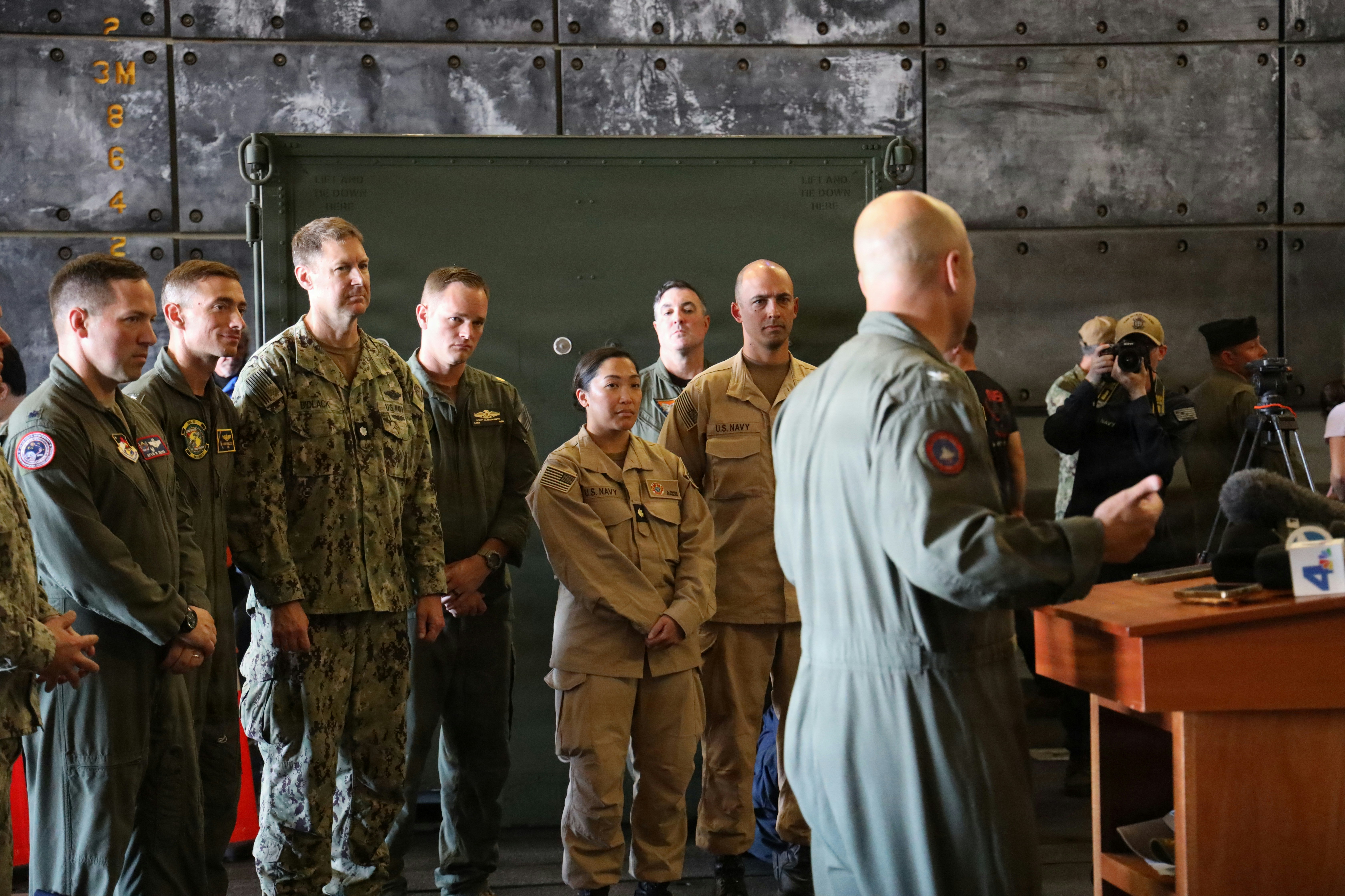 Military personnel gathered for a briefing indoors briefing indoors briefing