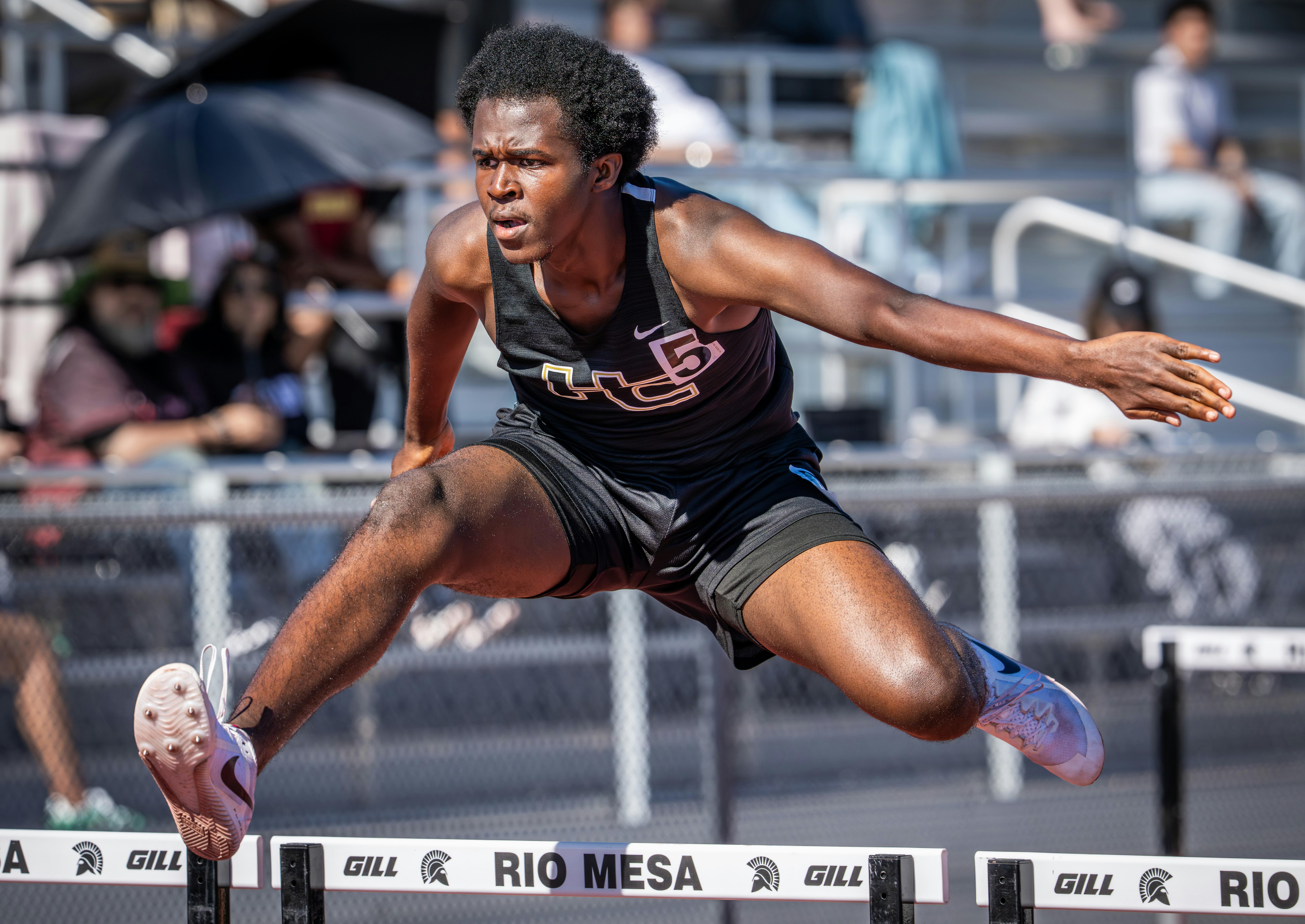 A male athlete hurdles during a track and field race.
