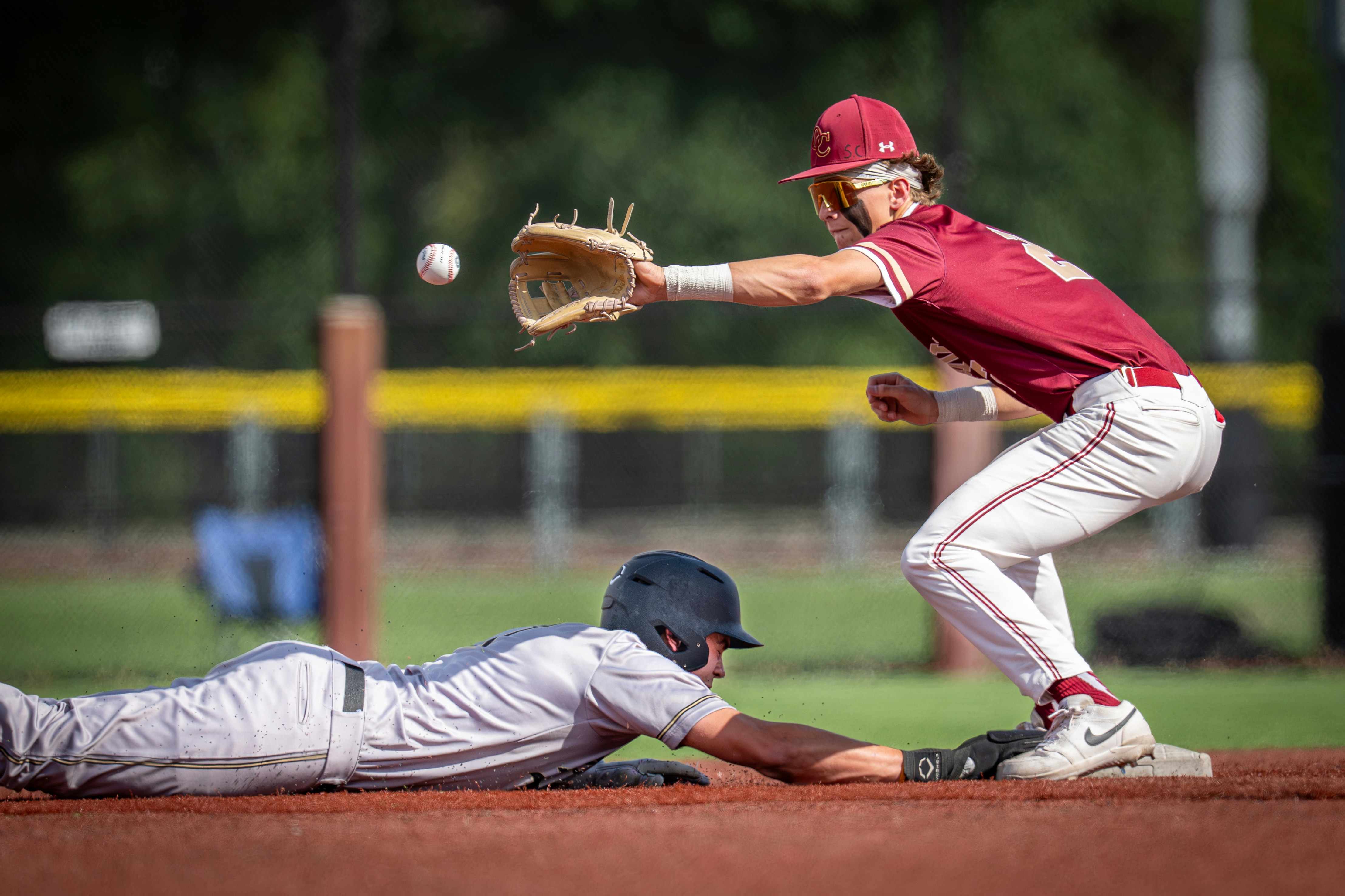 Baseball player slides into base as opponent attempts catch.