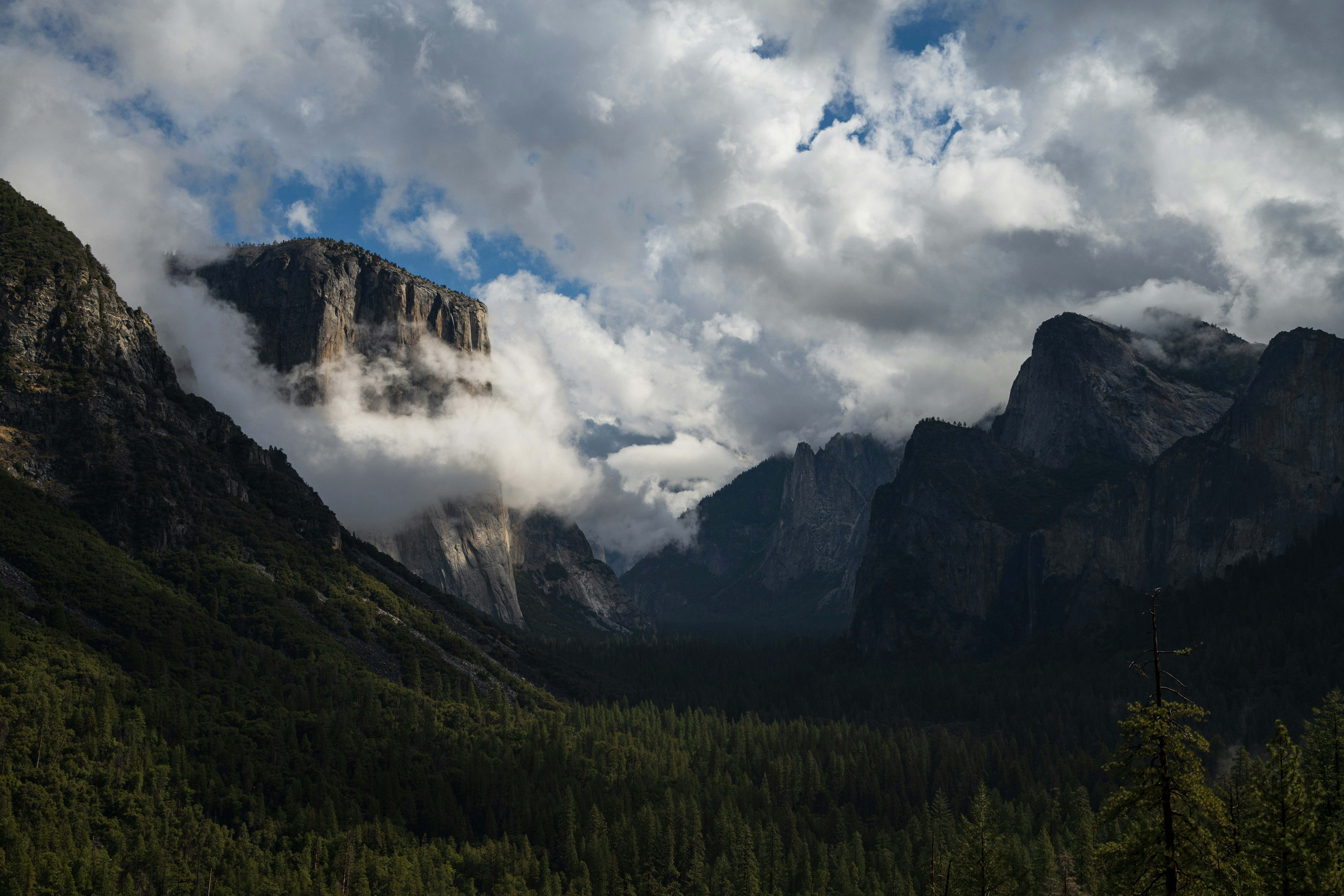 Dramatic clouds swirl around a majestic mountain valley.