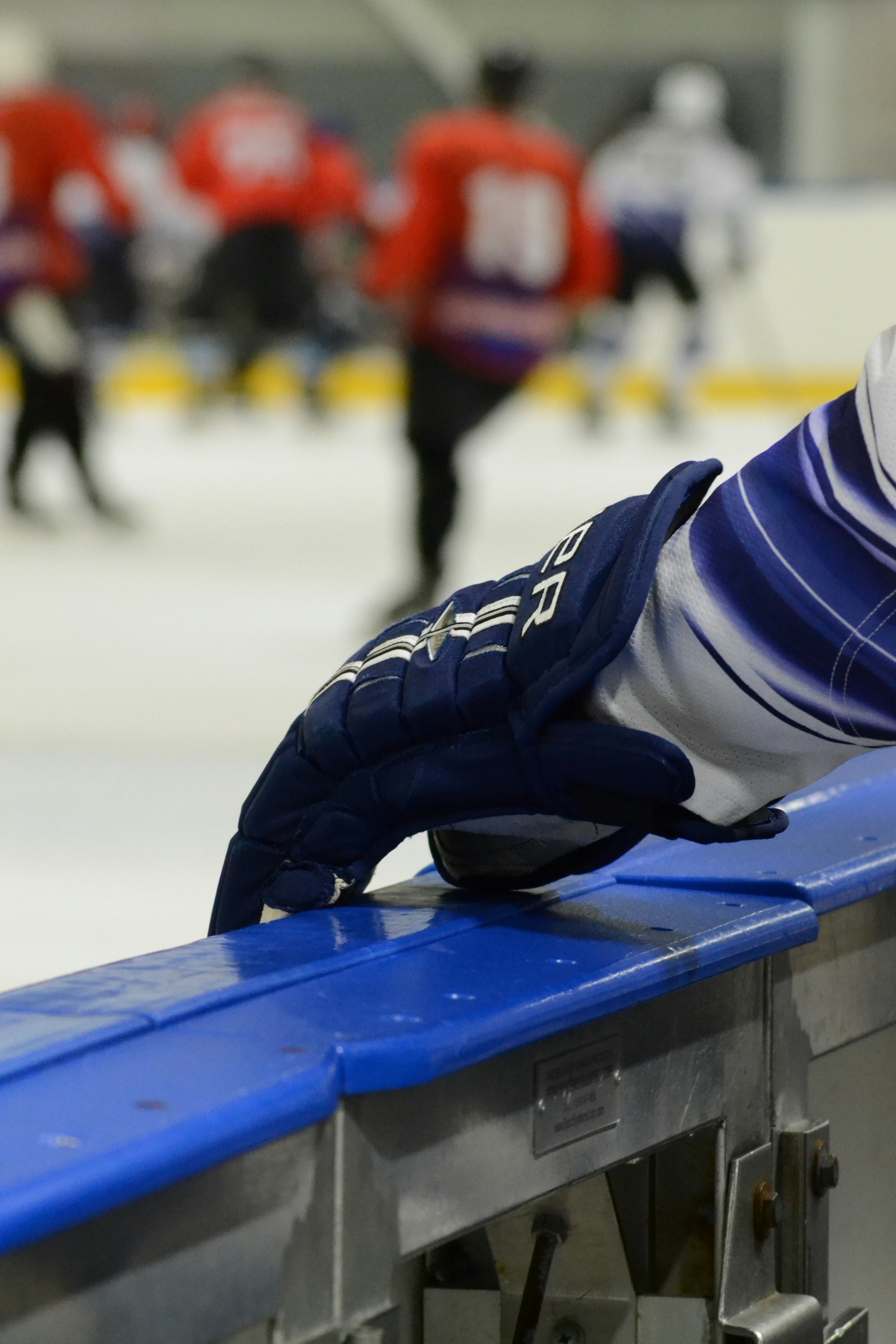 La mano guantata di un giocatore di hockey poggia sulle balaustre.