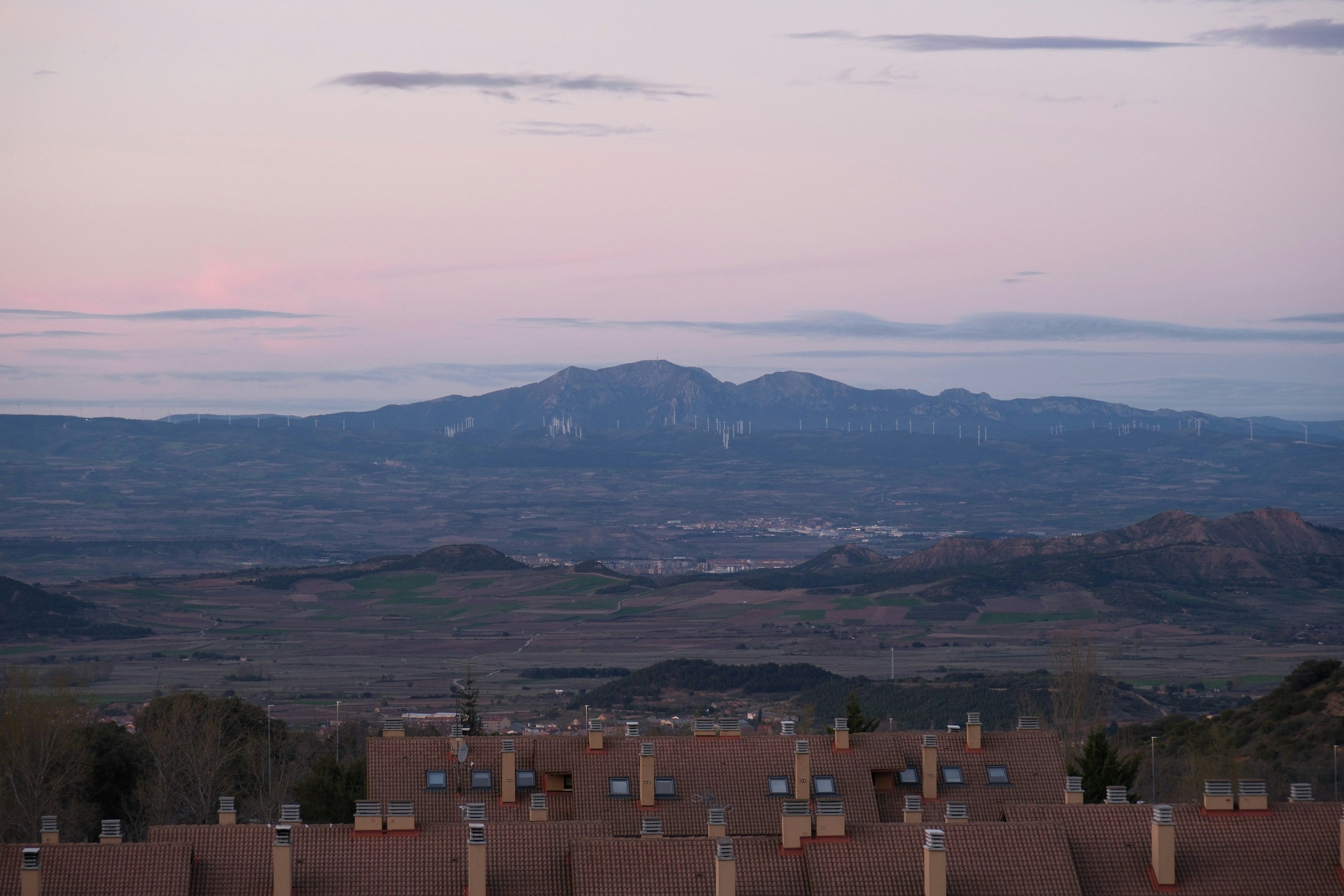 Montañas lejanas bajo un cielo rosa y púrpura.