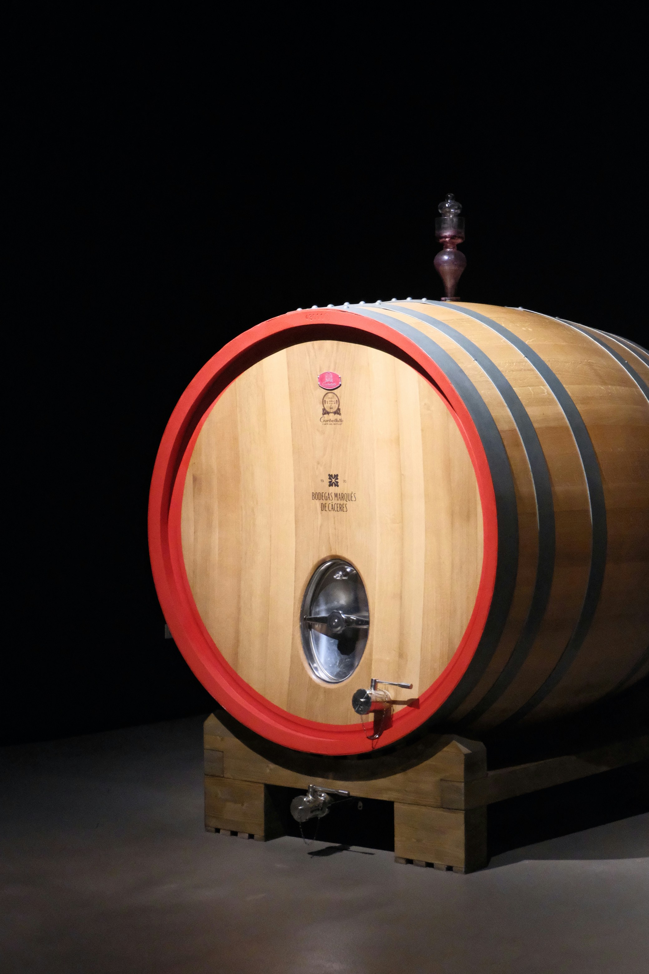 Un barril de vino de madera con detalles rojos en los extremos