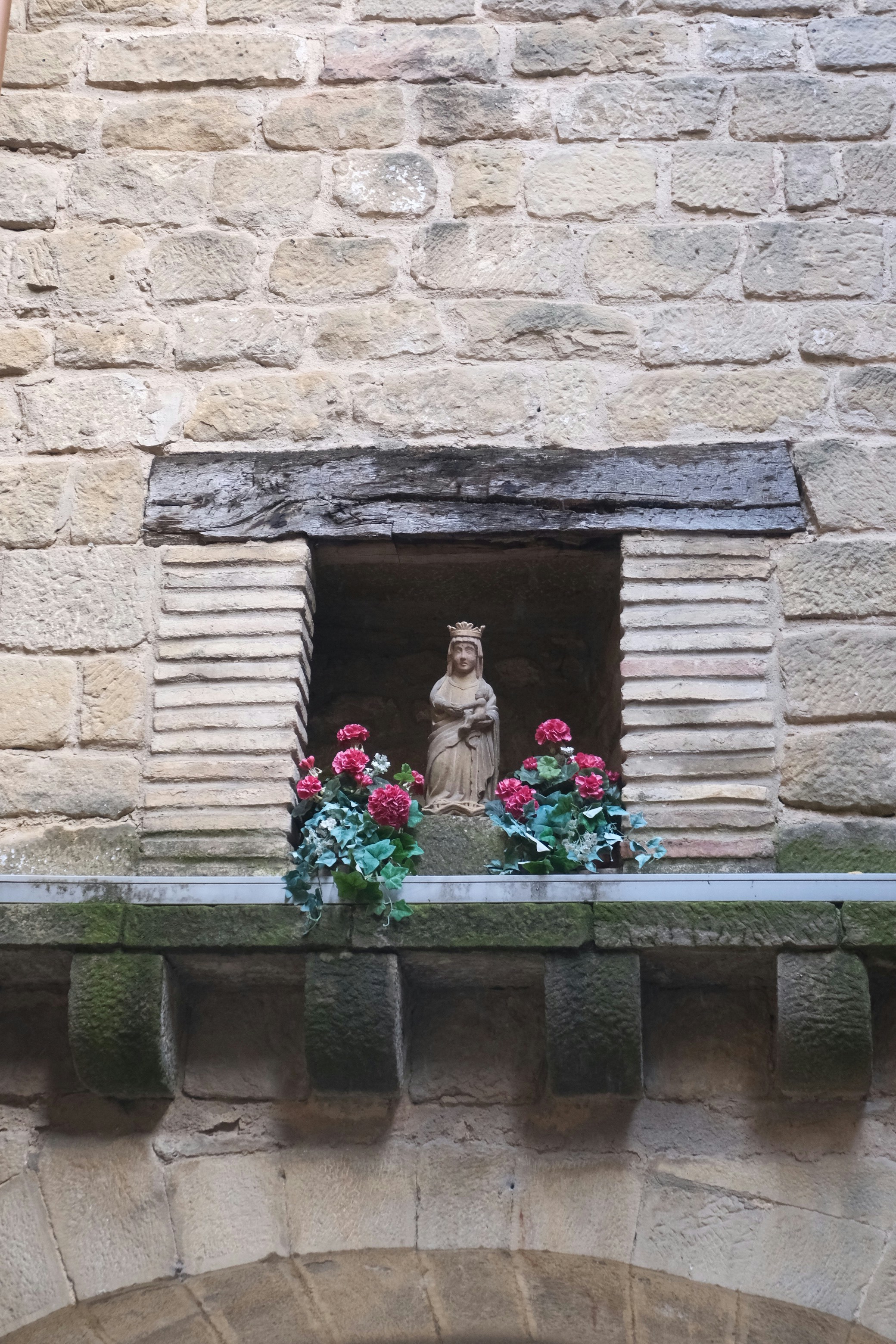 Estatua de piedra de una figura coronada con flores