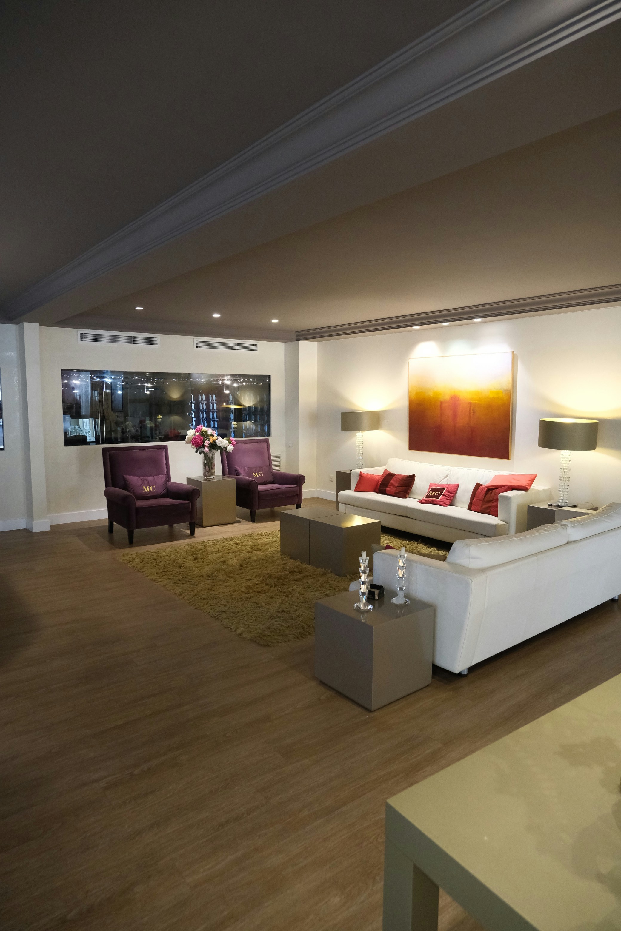 Salón moderno con sofá blanco y sillones morados.