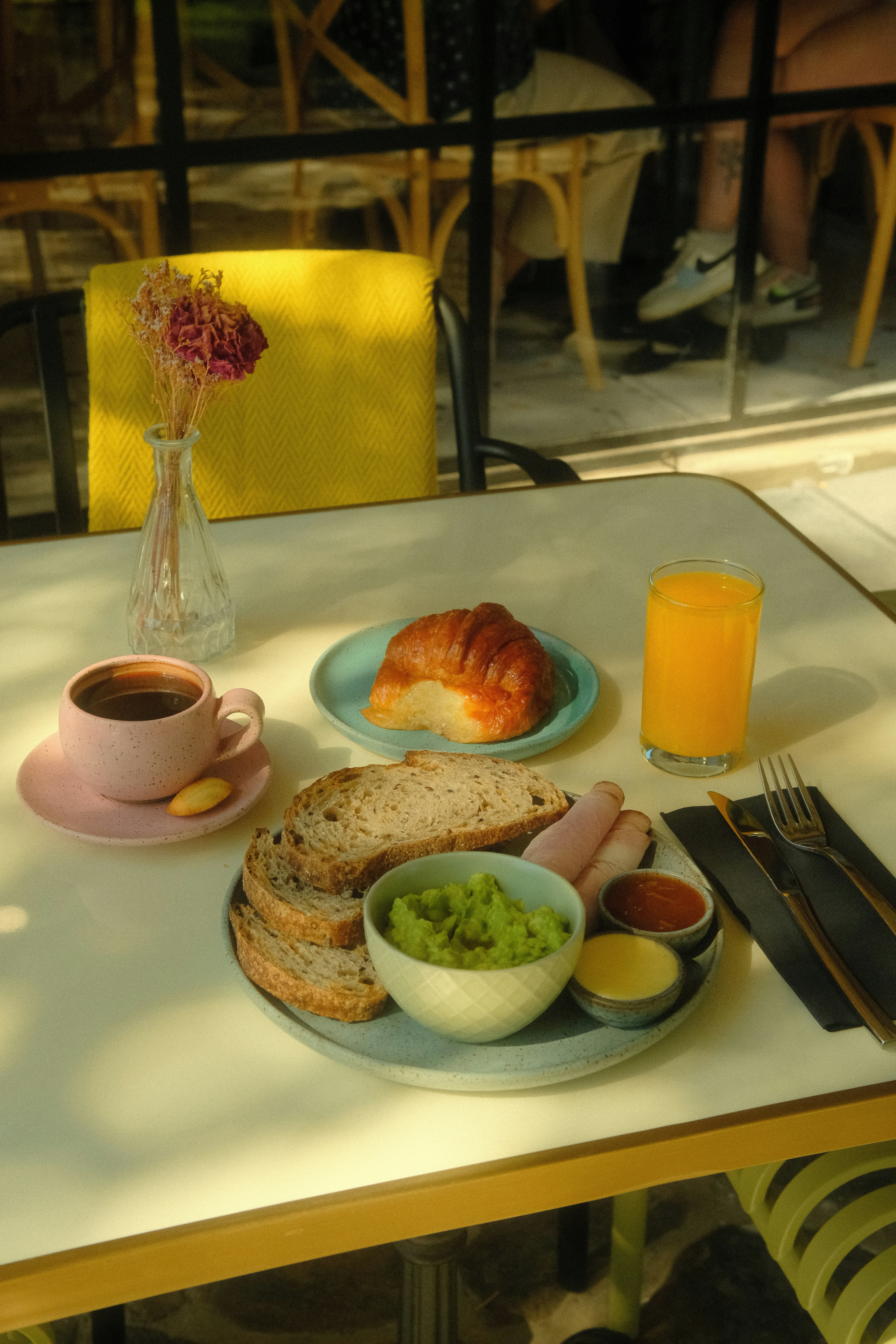 A breakfast spread with coffee, croissant, and avocado toast.