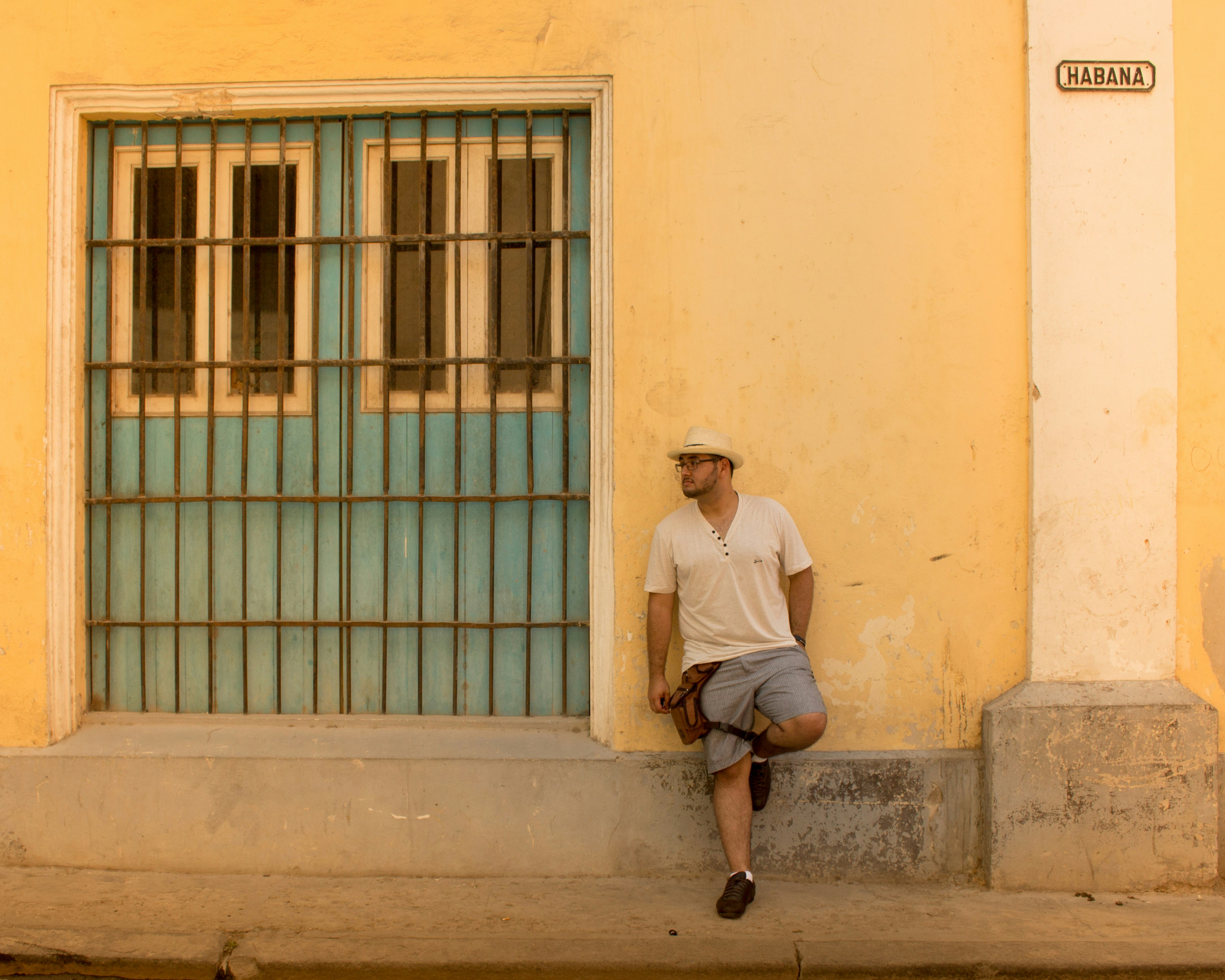 Un emprendedor cubano mira por la ventana al amanecer, con una expresión pensativa y decidida, simbolizando la planificación y la mentalidad emprendedora.