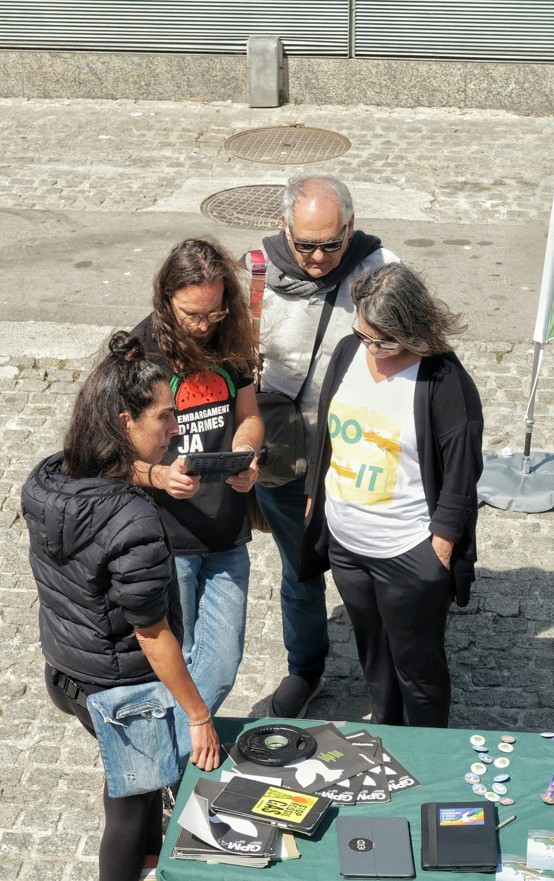 Four people gathered around a tablet on a table.