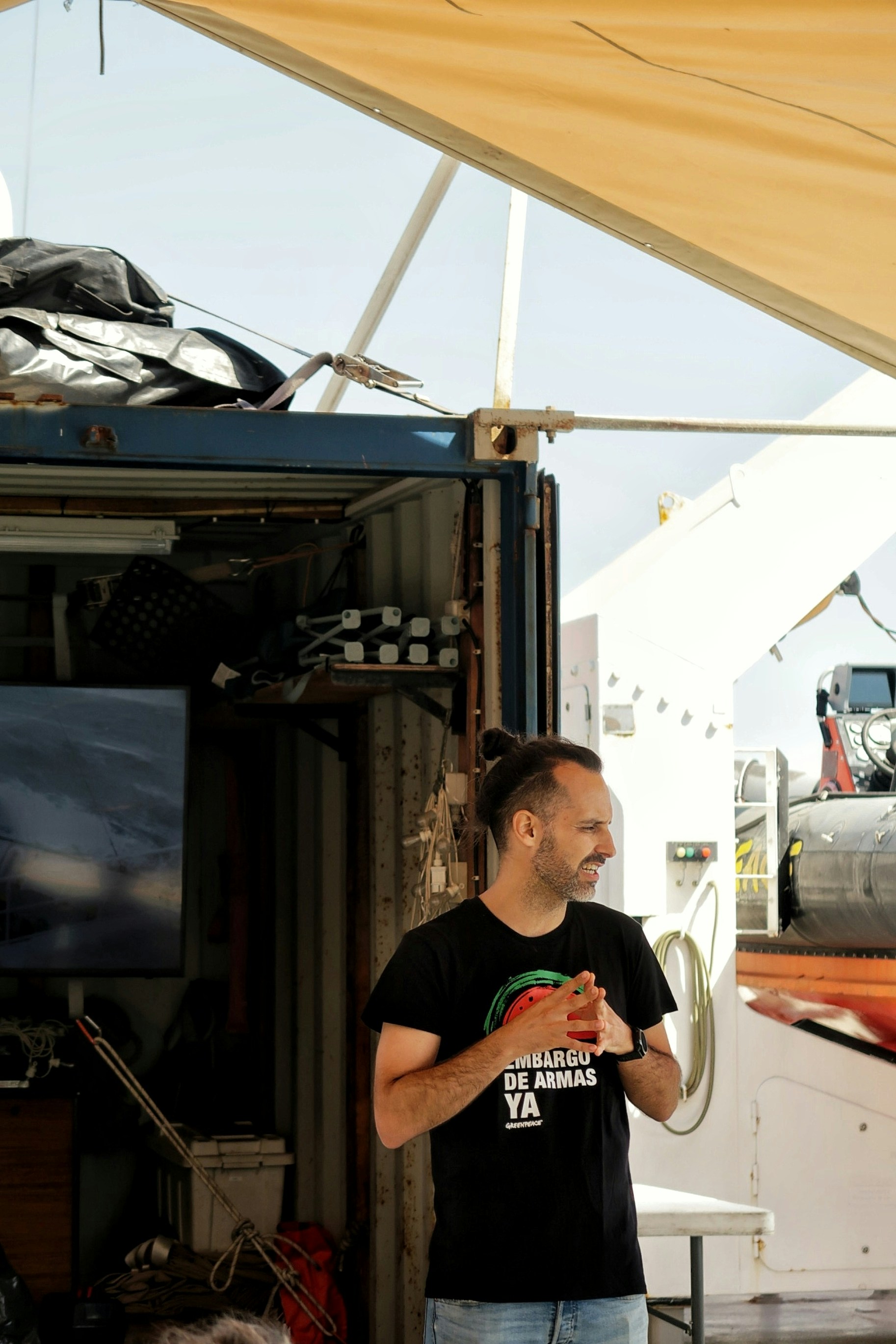 Homme en t-shirt noir avec un logo vert et rouge.