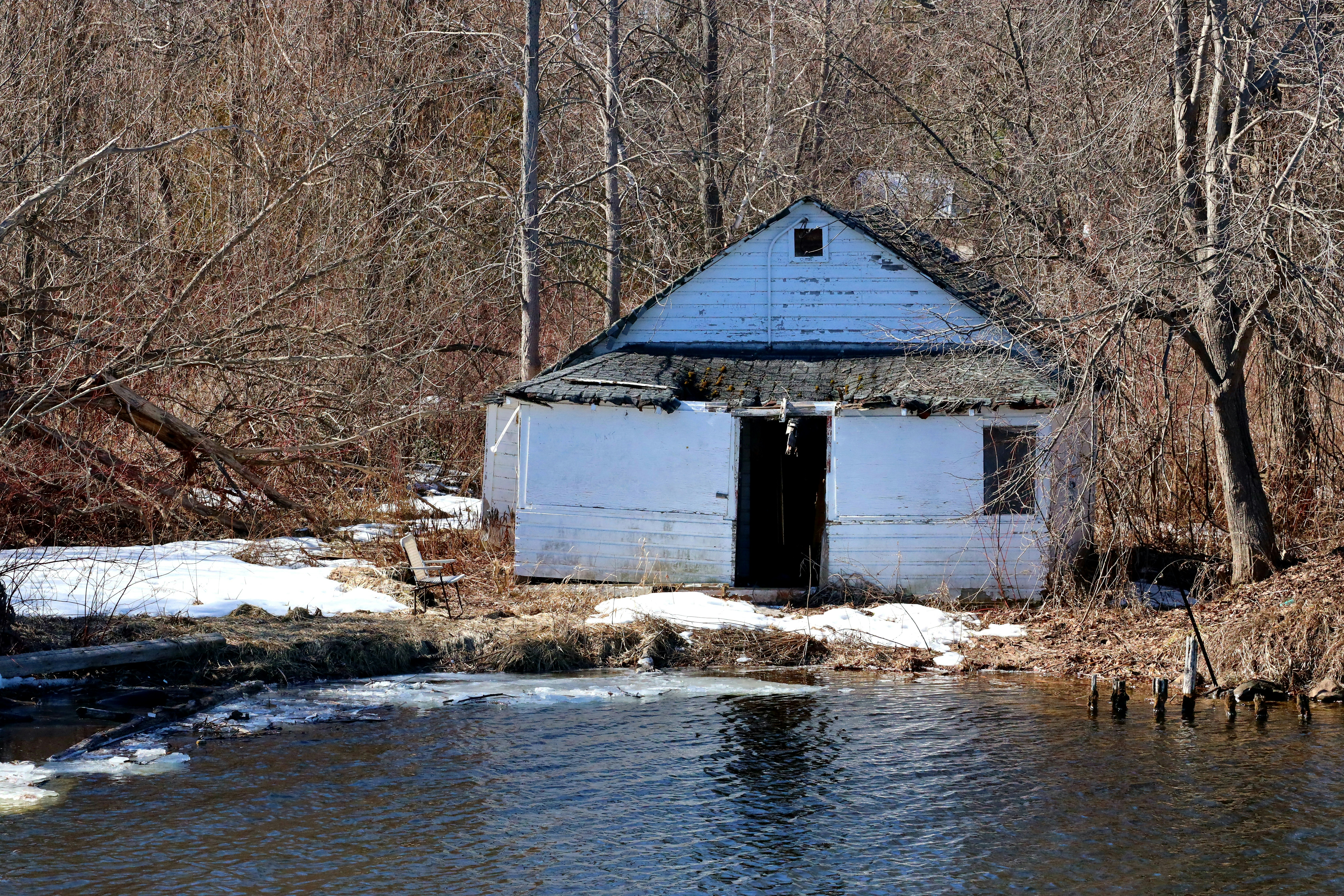 Maison blanche abandonnée au bord d’une rivière en hiver