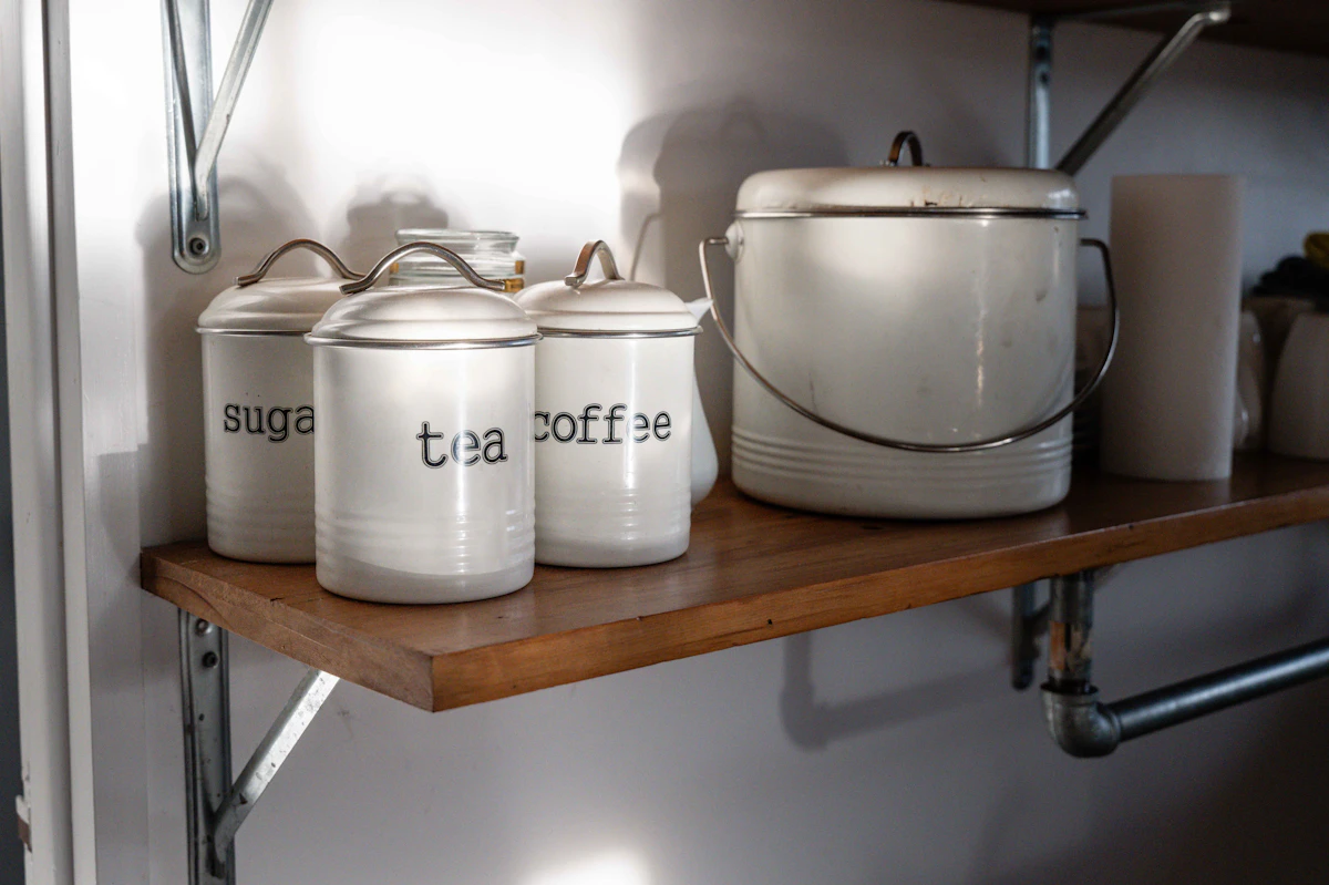 White canisters labeled sugar, tea, and coffee on a shelf