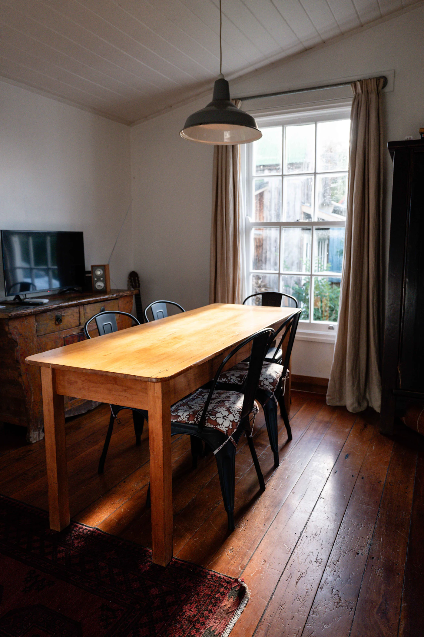 Dining area with a wooden table beside a tall window