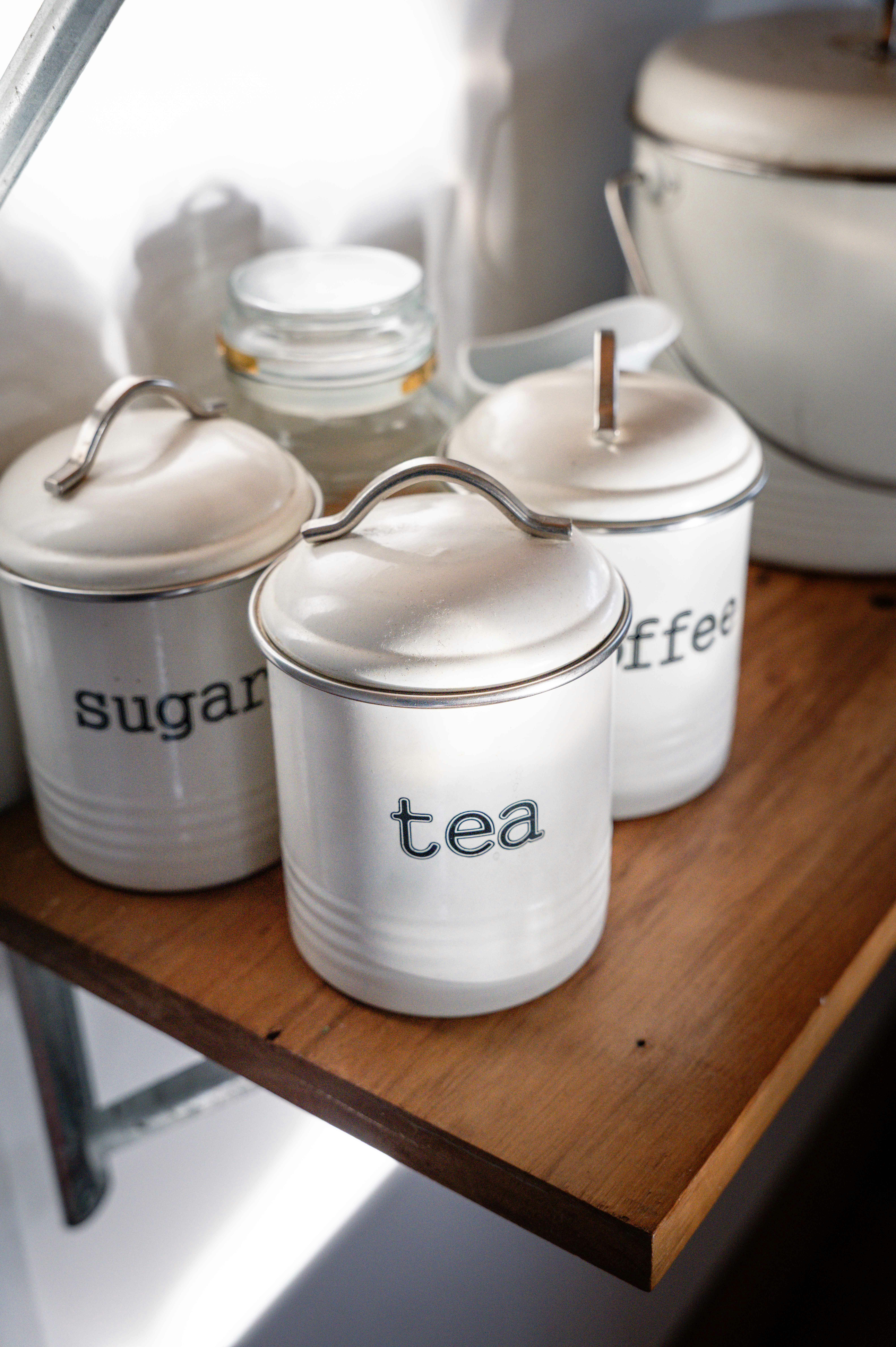 Los botes blancos de cocina etiquetaban té, azúcar y café.