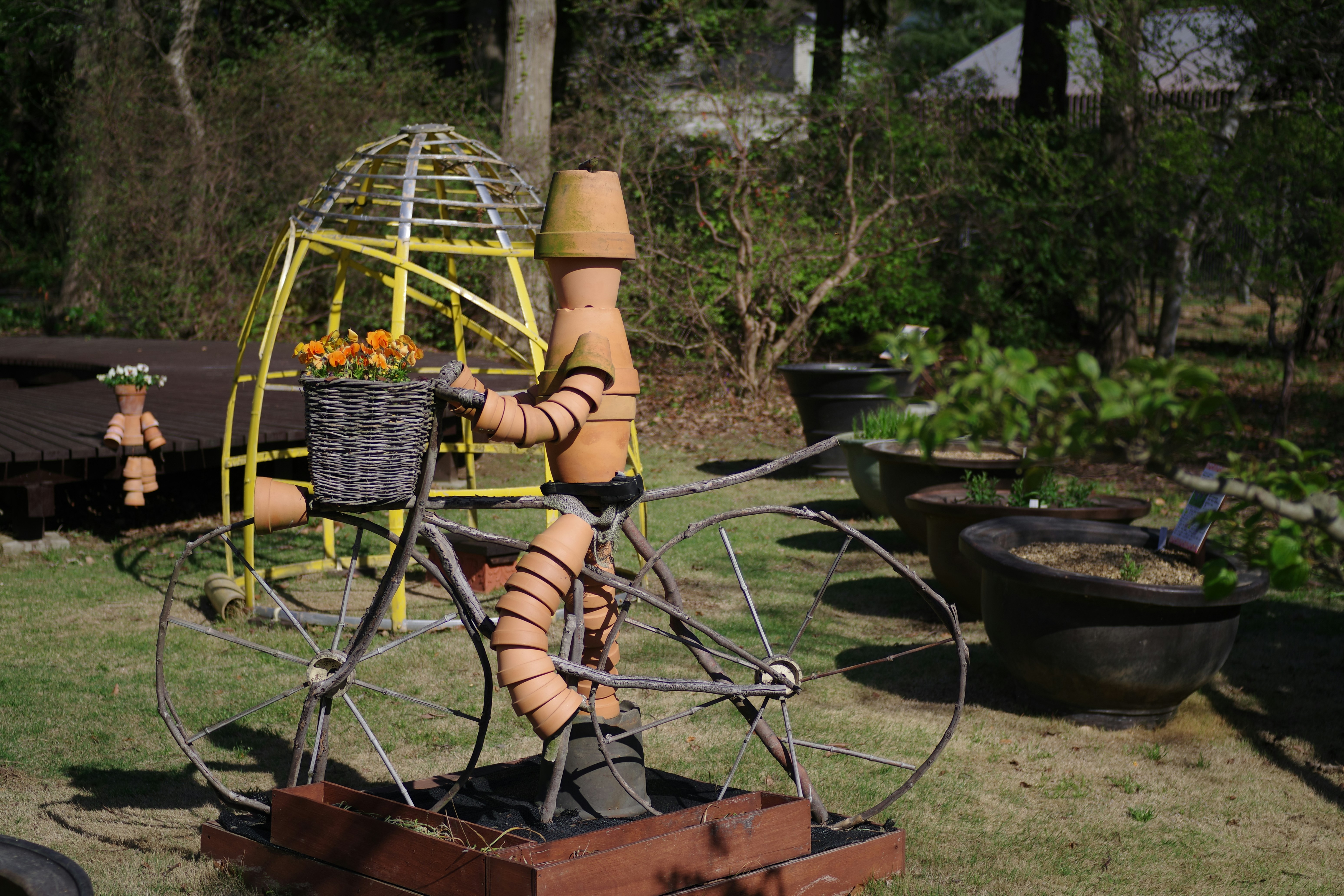Clay figure on a bicycle with flowers in basket.