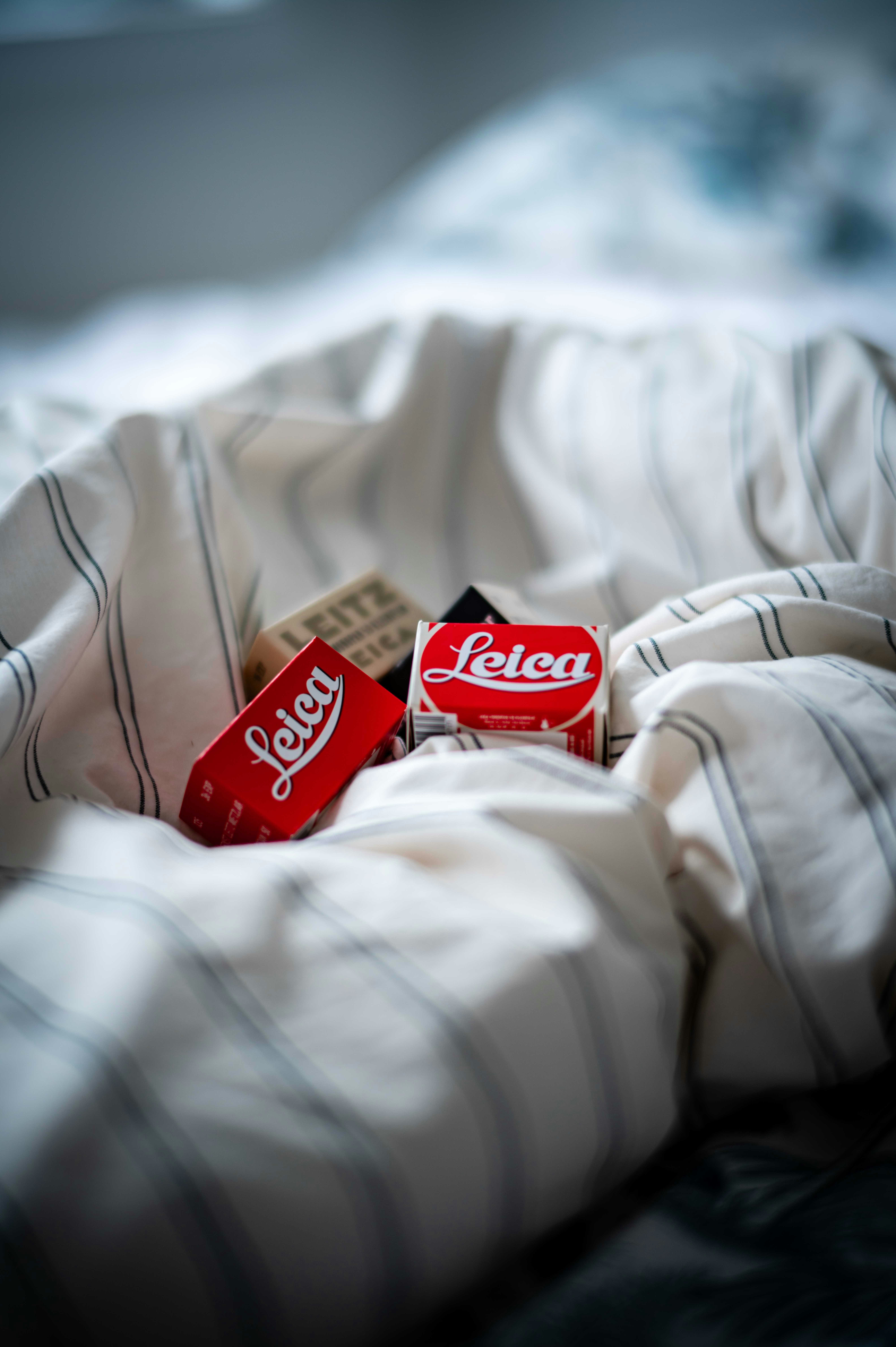 Three red leica film boxes on a striped blanket