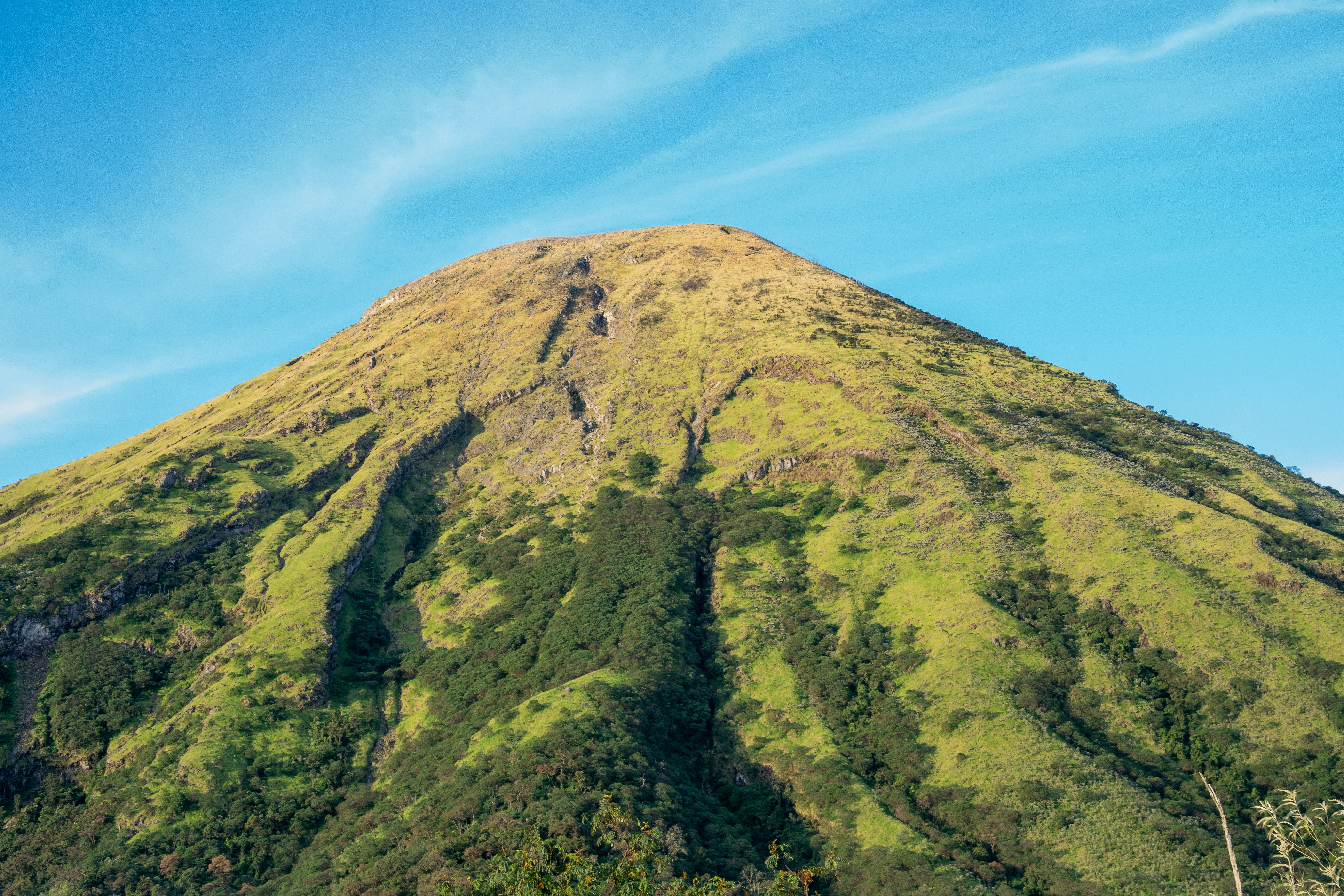 Montanha verde de grama sob um céu azul claro