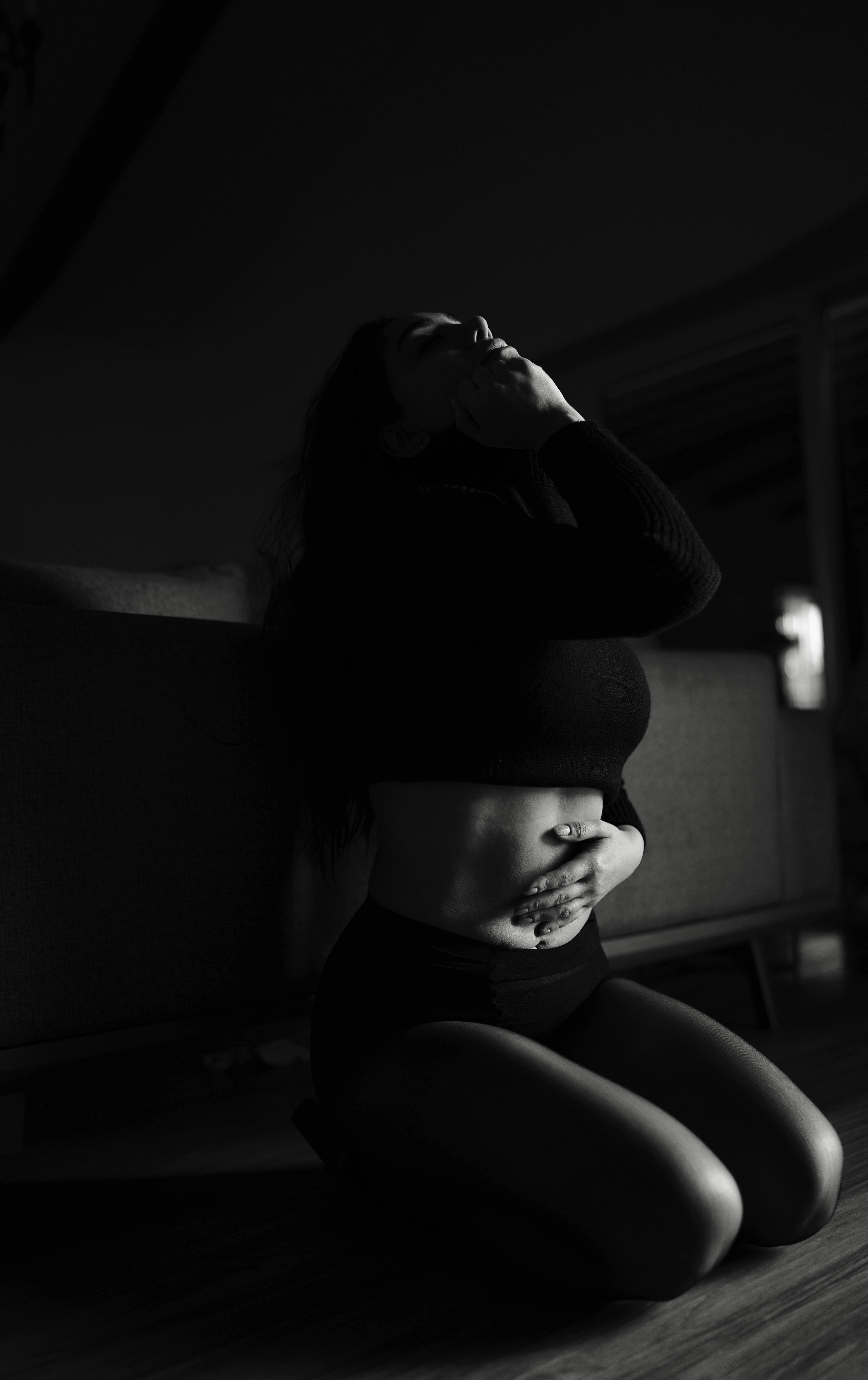 Woman kneeling on floor, hands on stomach and near stomach.