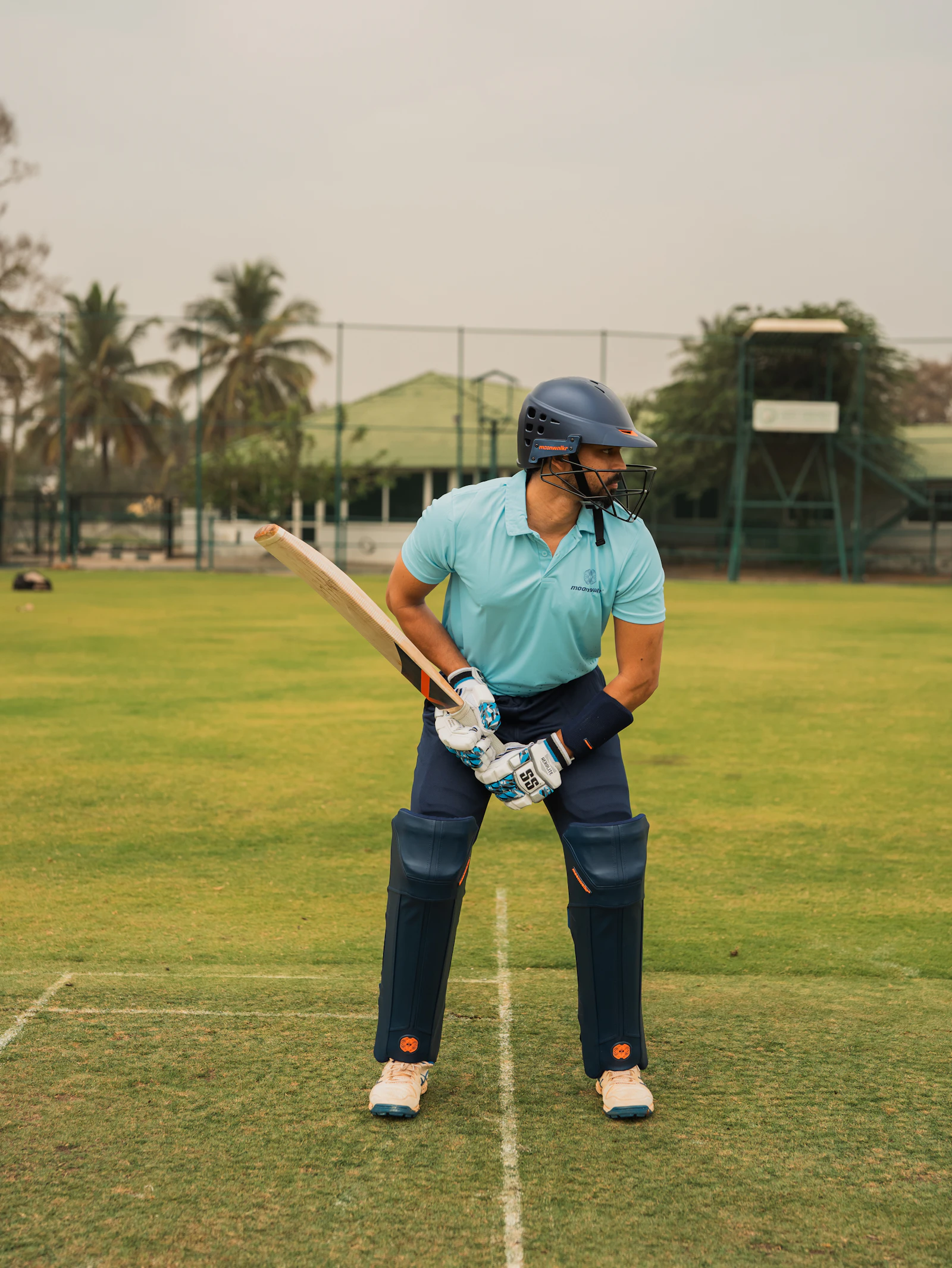 Cricketer in batting stance on a green field