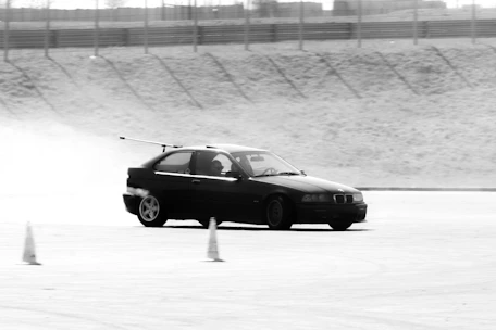 Black car drifting around cones on track