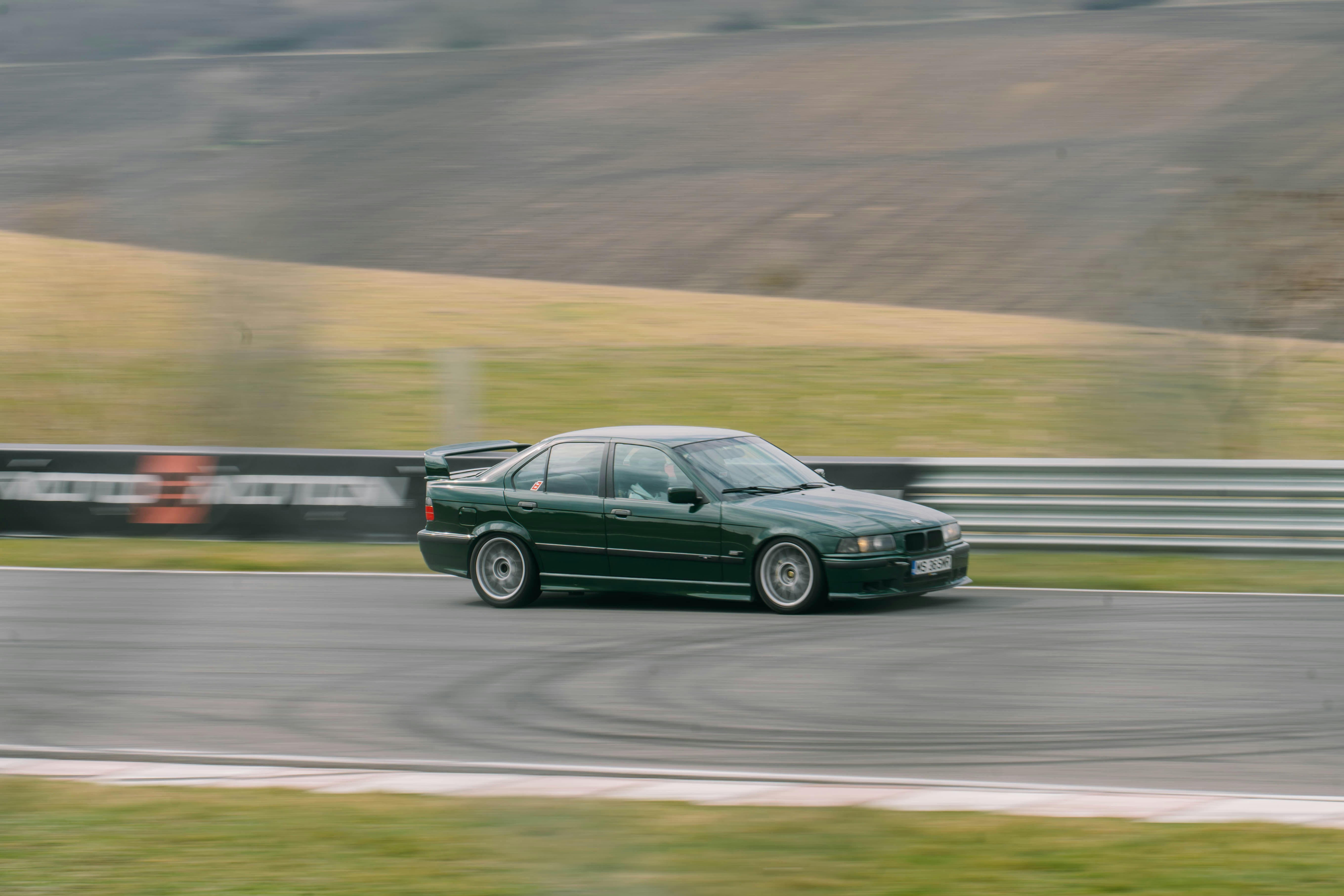 Una berlina verde scuro che guida su una pista.