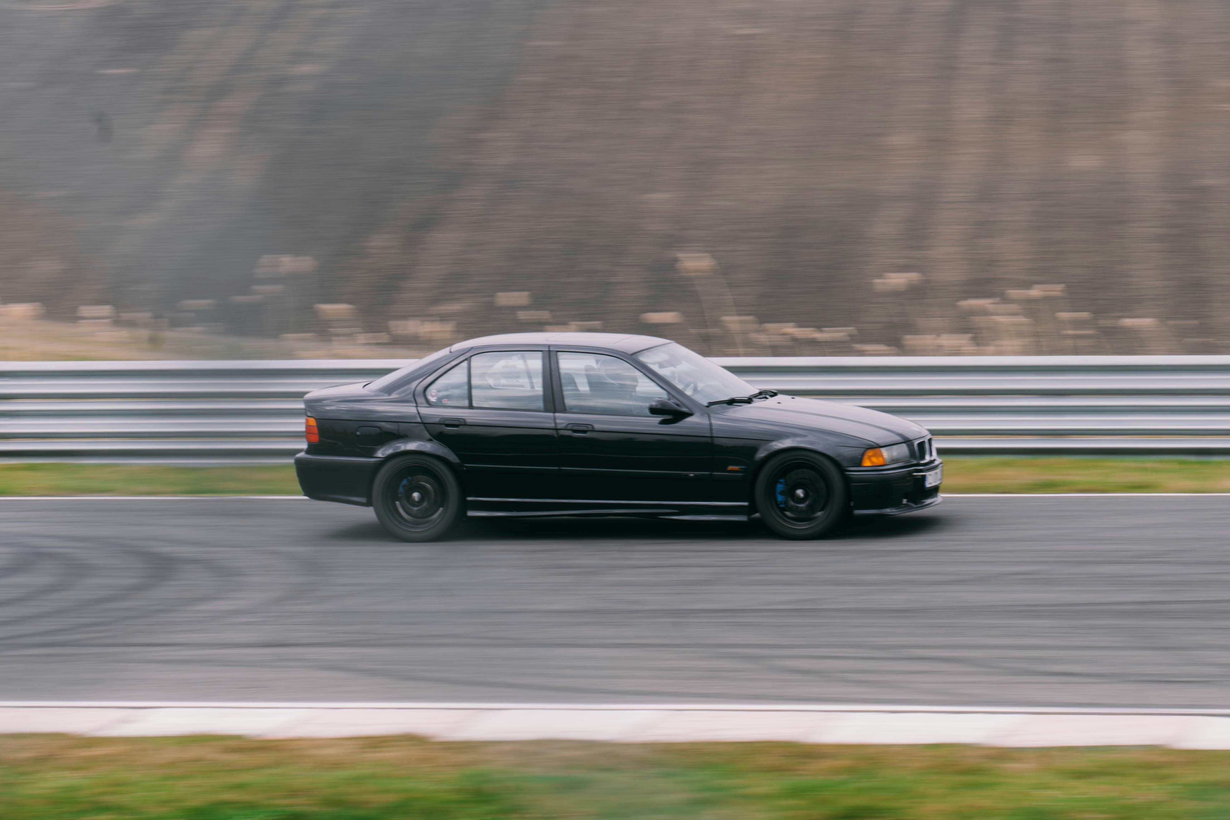 Una berlina nera guida su una pista da corsa.