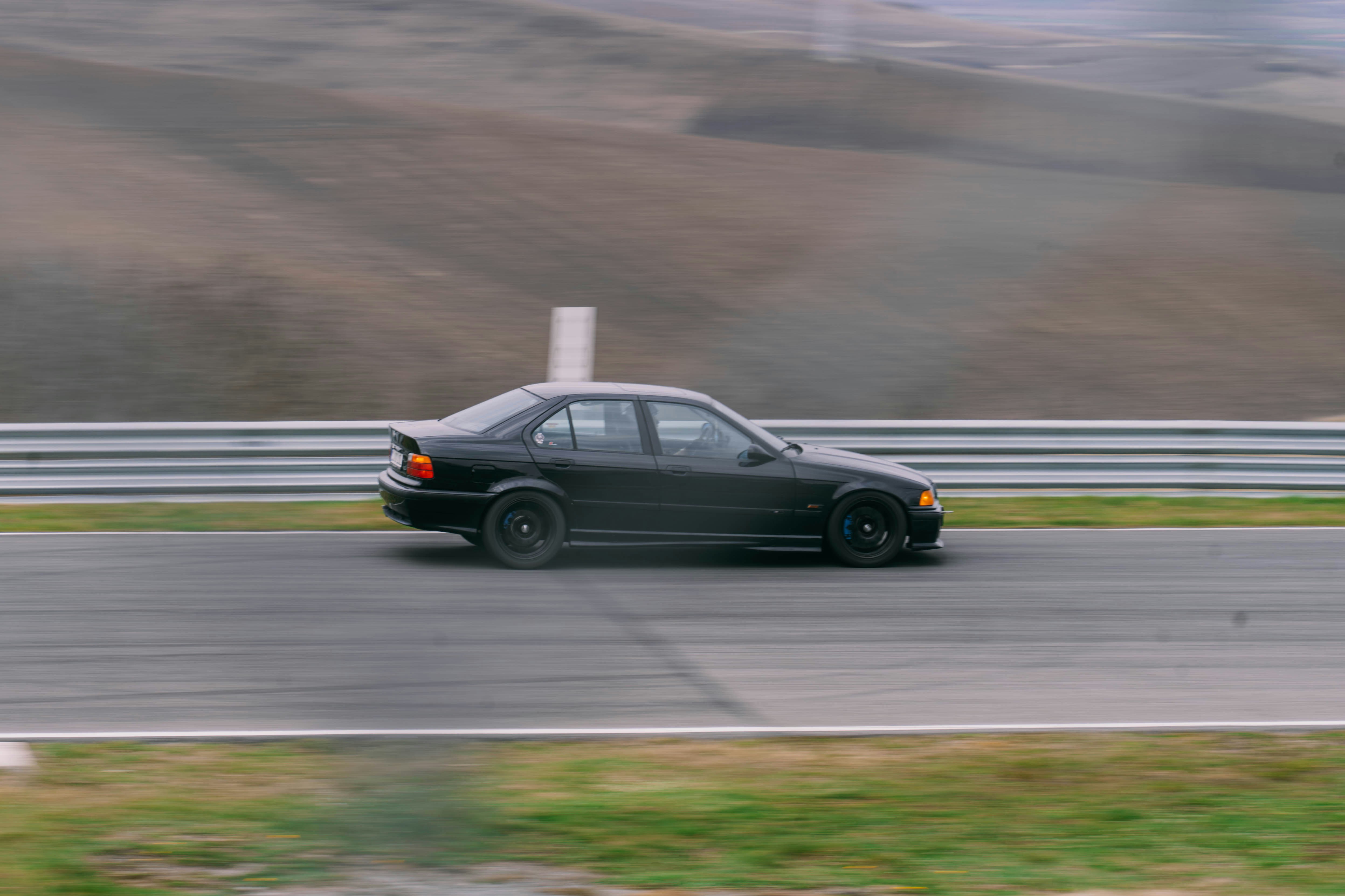 Una berlina nera guida su una pista.