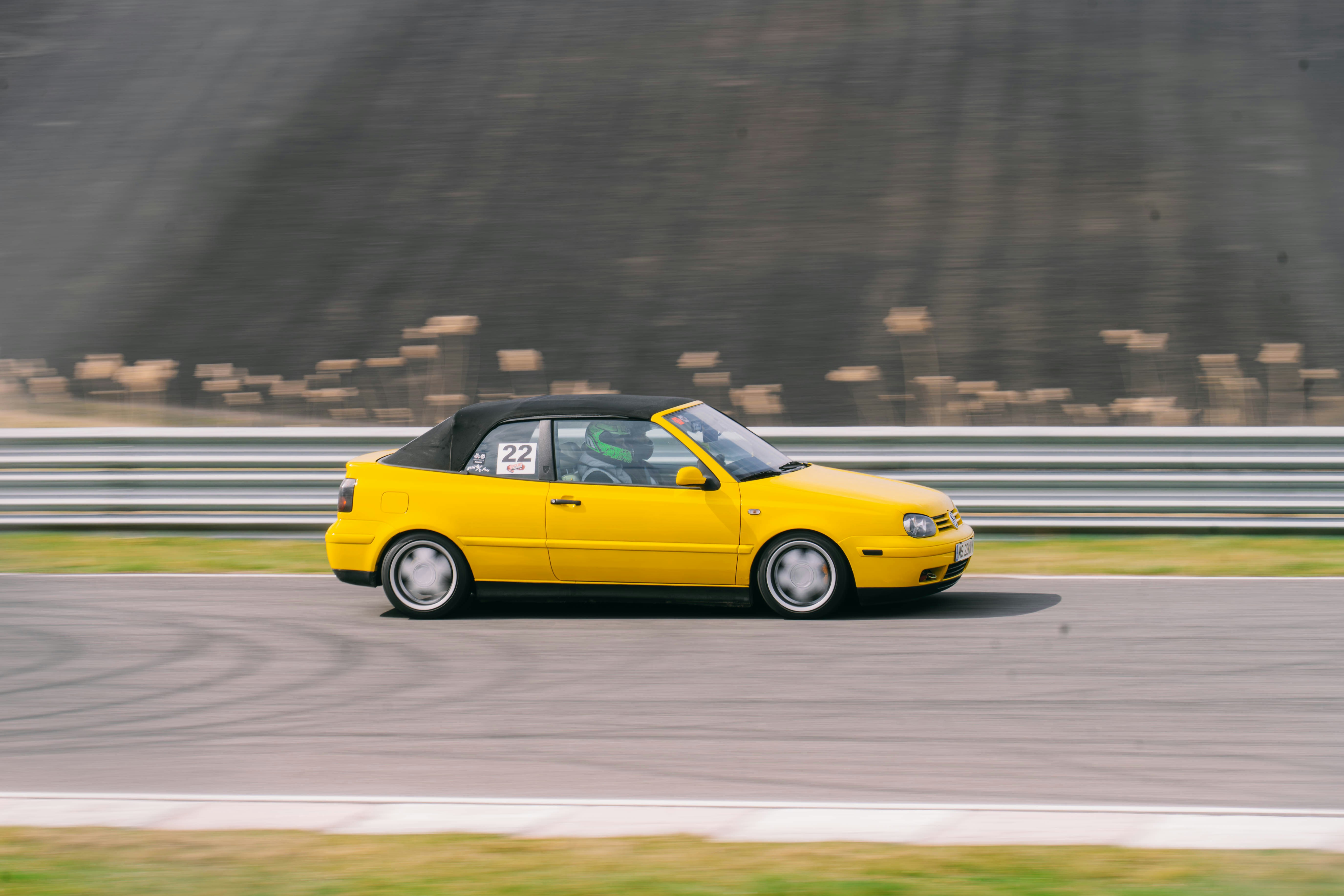 Una cabriolet gialla che guida su una pista da corsa