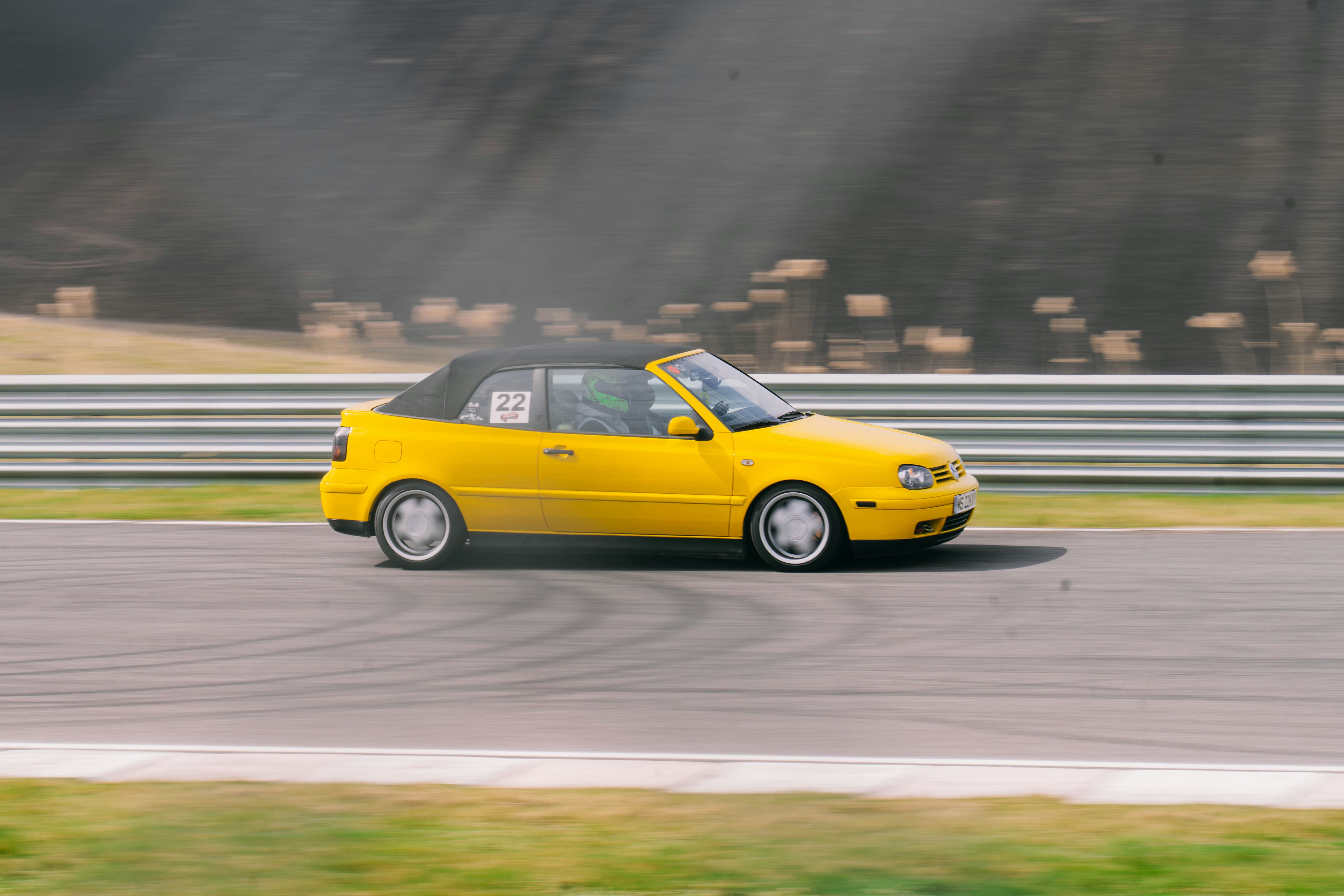 A yellow convertible car races on a track
