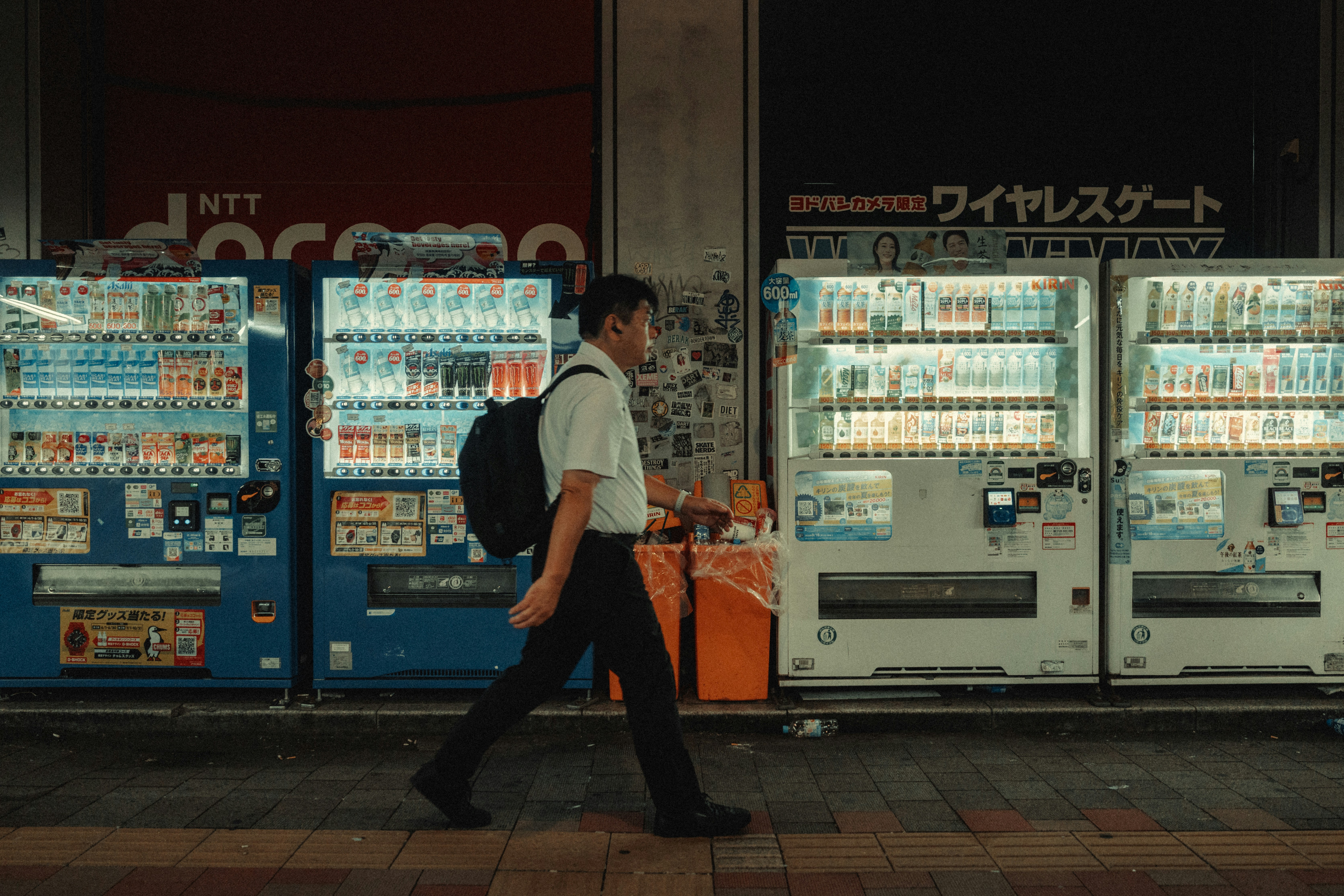 a man is walking past vending machines in the city
