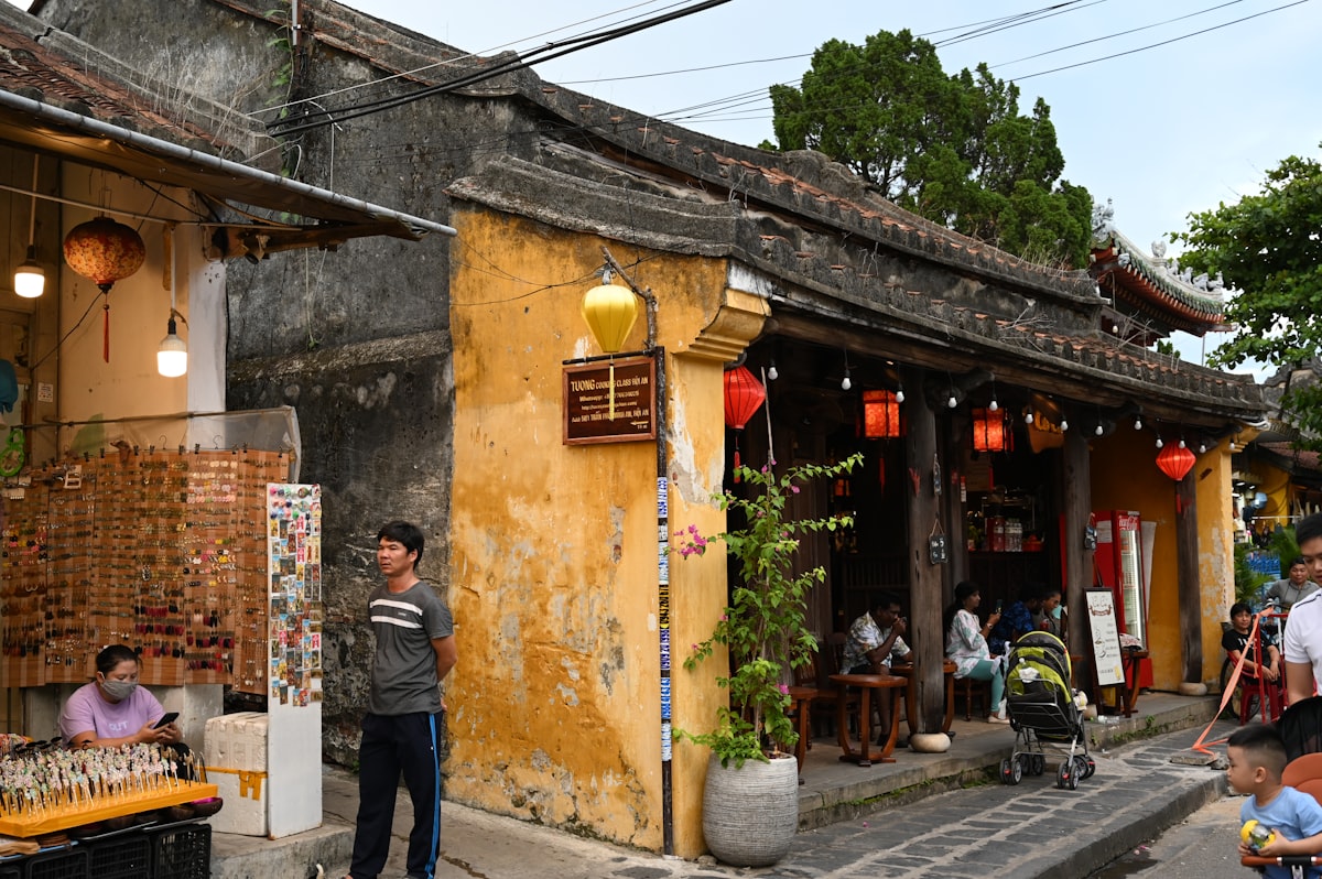 Hoi An April — sunlit old street with traditional yellow shophouses and visitors exploring the Ancient Town