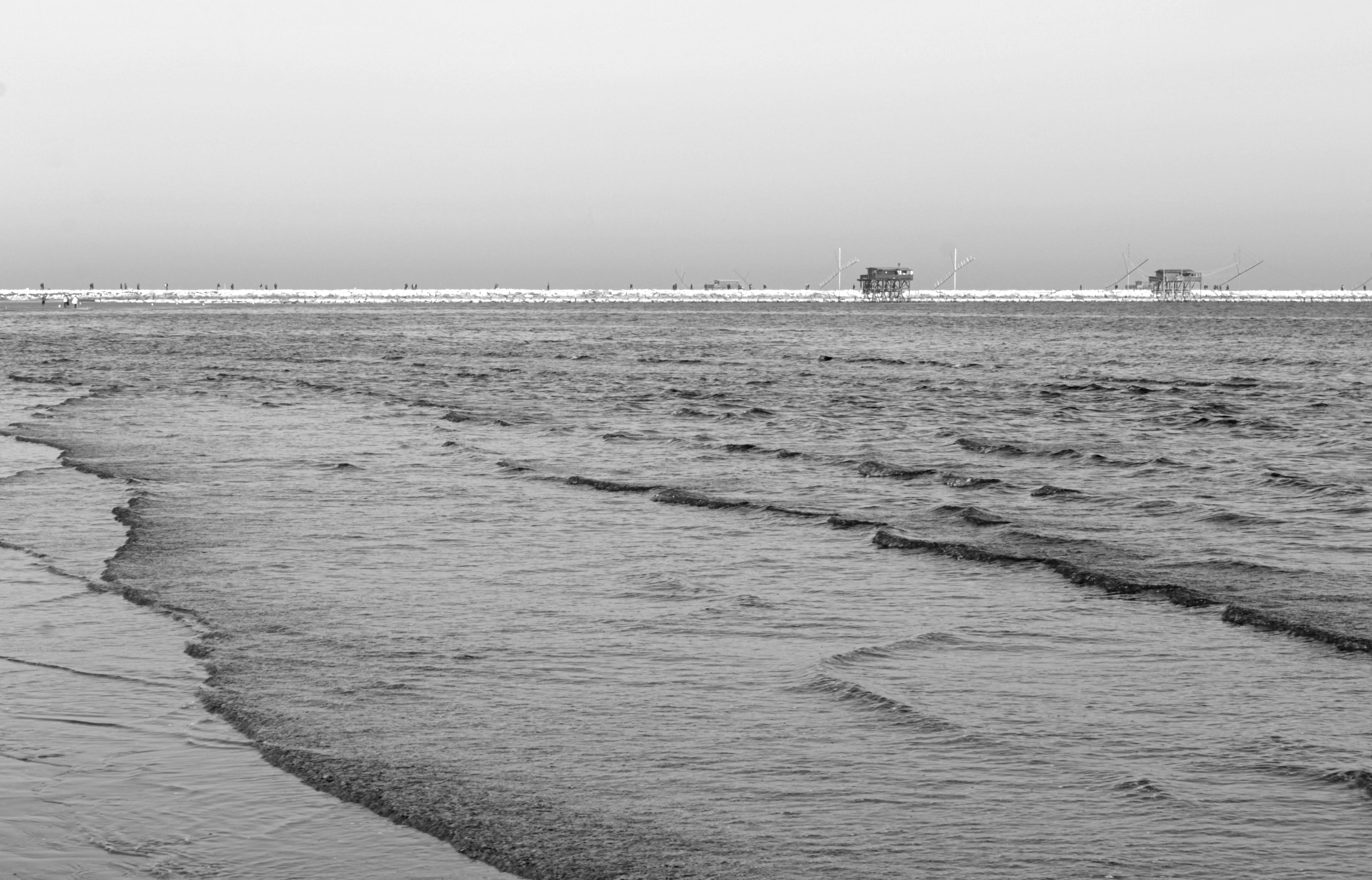 Two small buildings on a distant pier over calm water