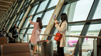 Two women taking selfies by airport window