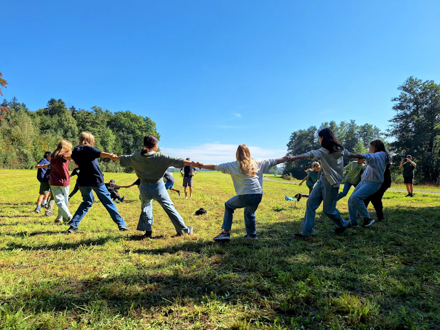 Young people playing tug-of-war together on a grassy field