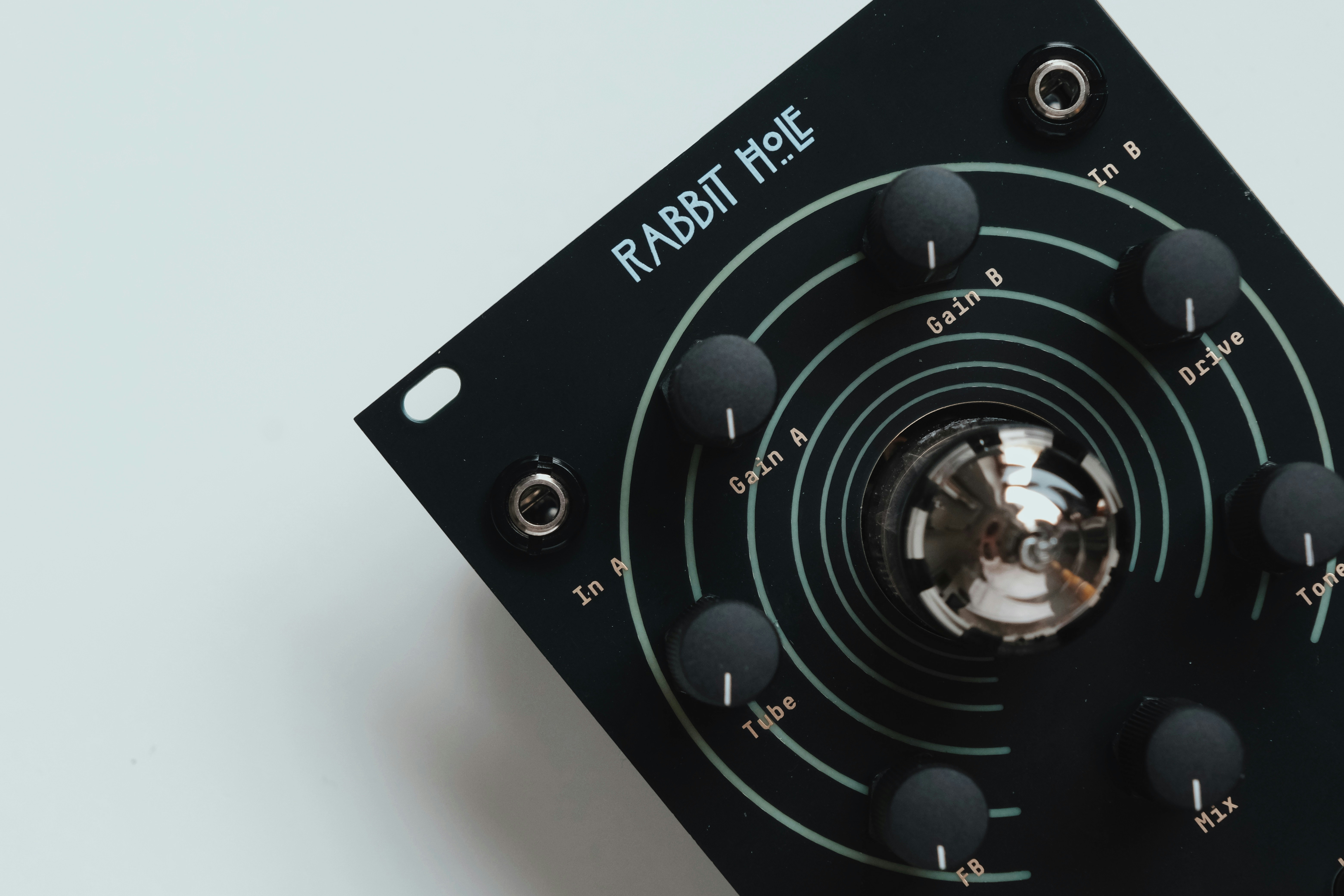 Black electronic device with knobs and a central glass tube