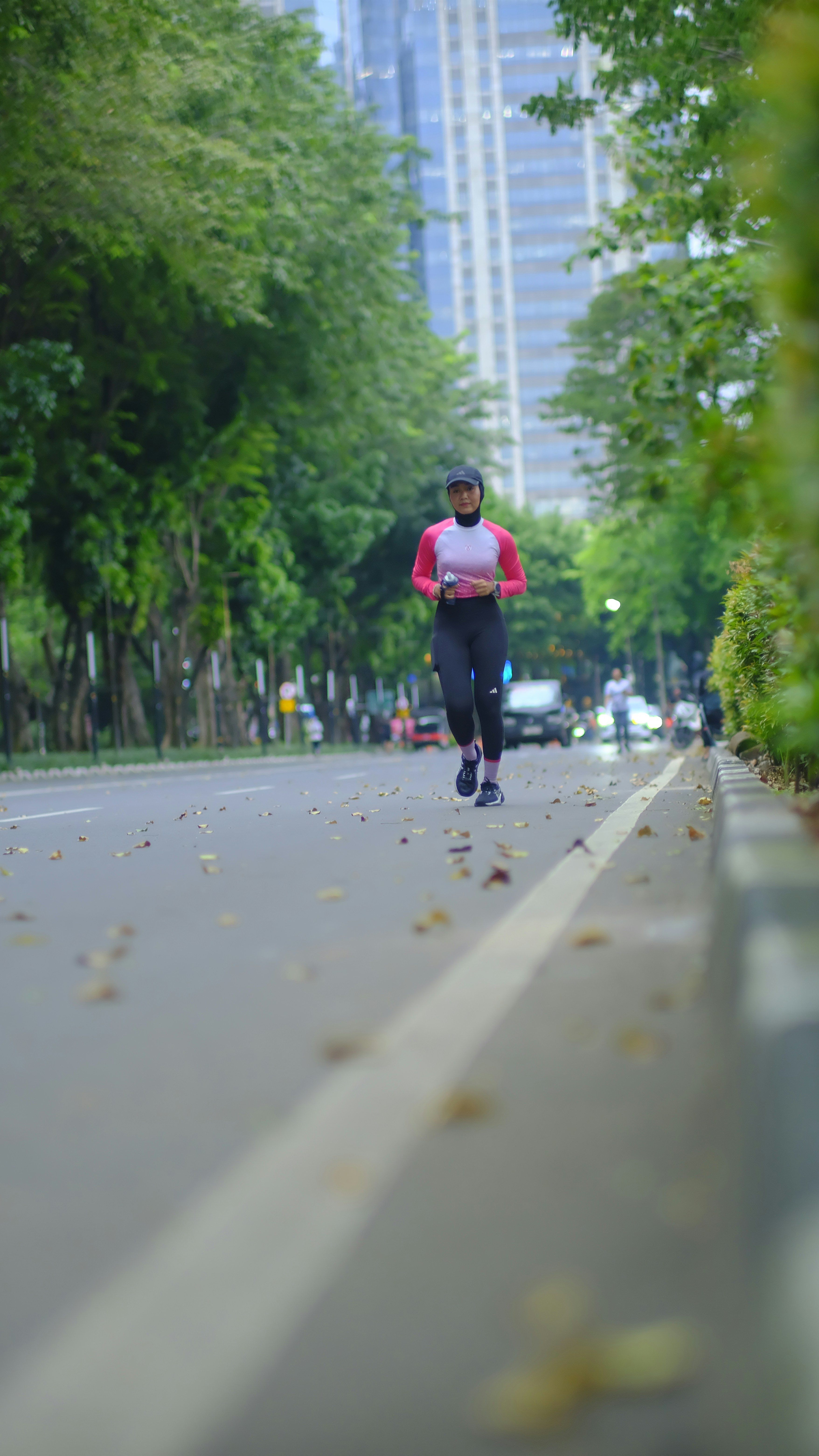 Uma mulher corre por uma rua arborizada na cidade.