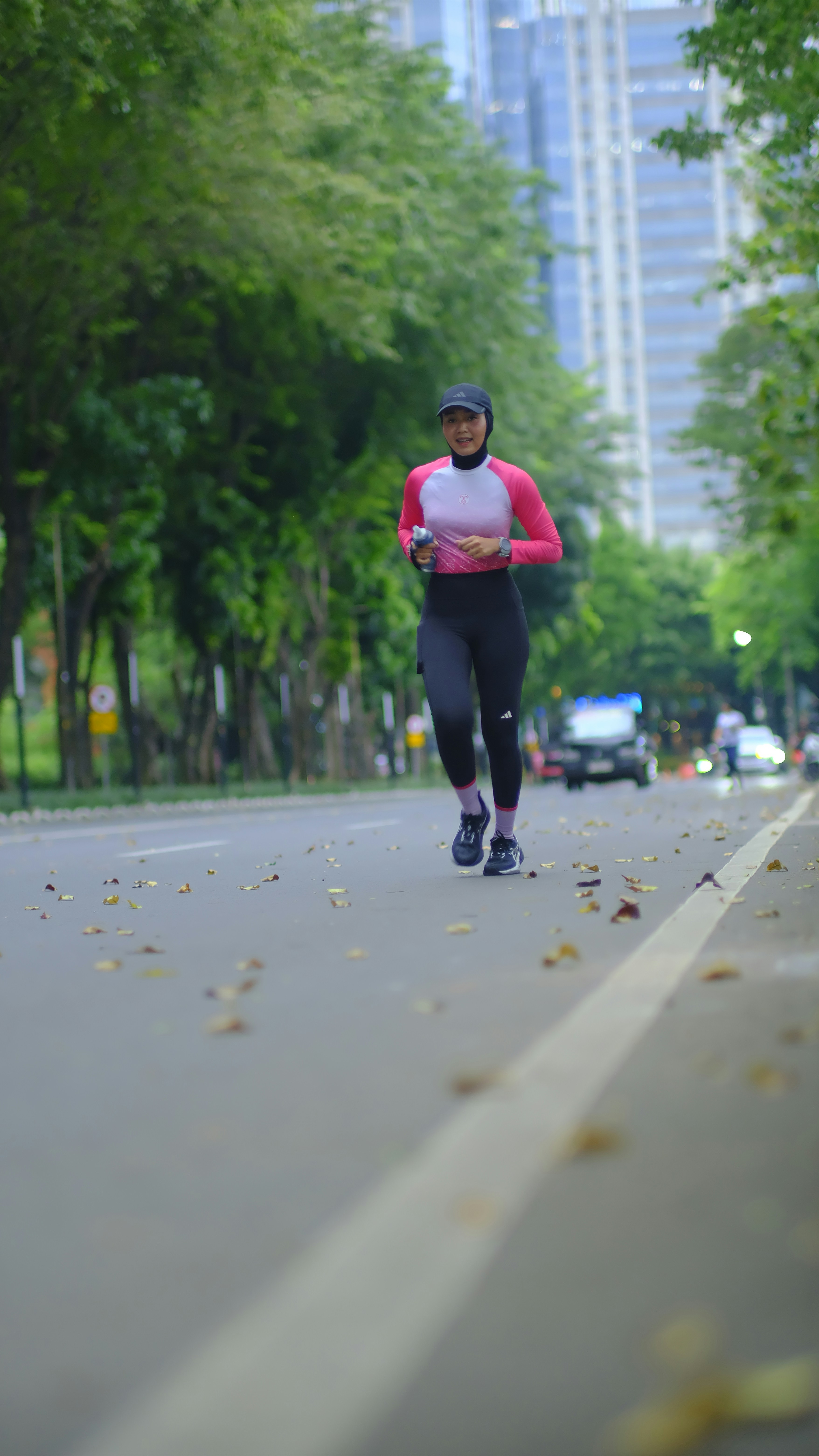 A woman in athletic wear runs on a paved road.