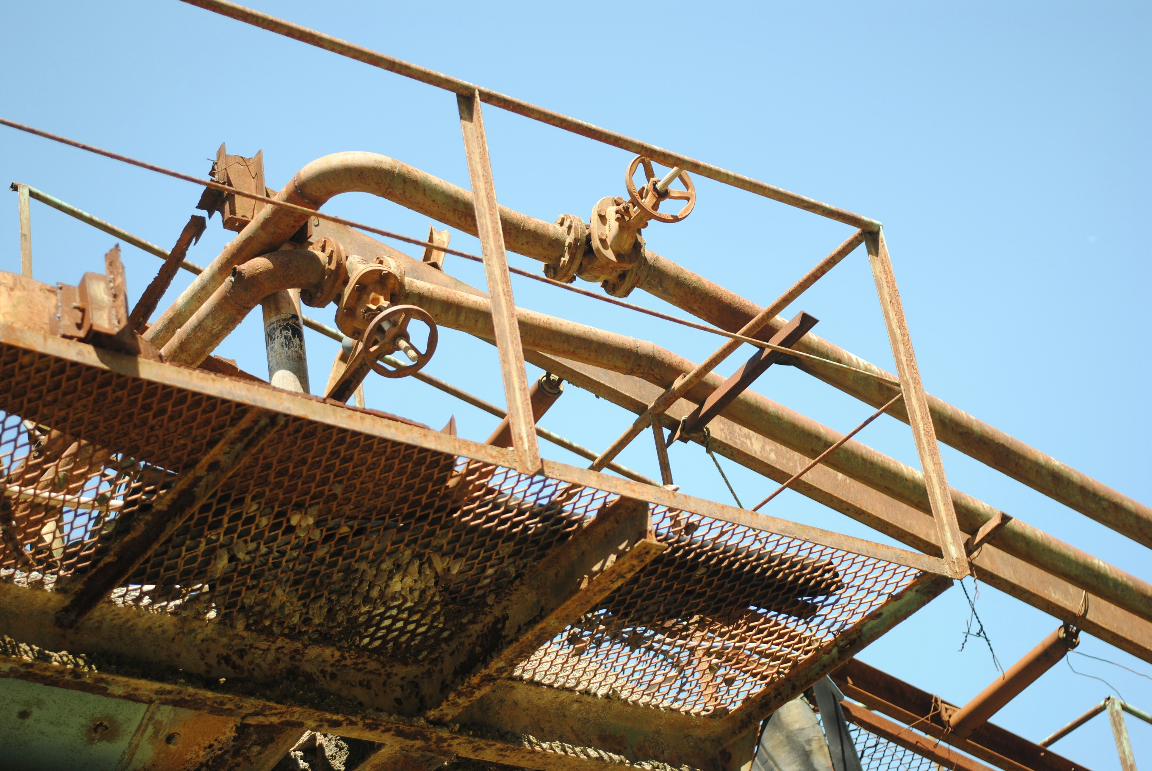 Rusty industrial pipes and platform against blue sky