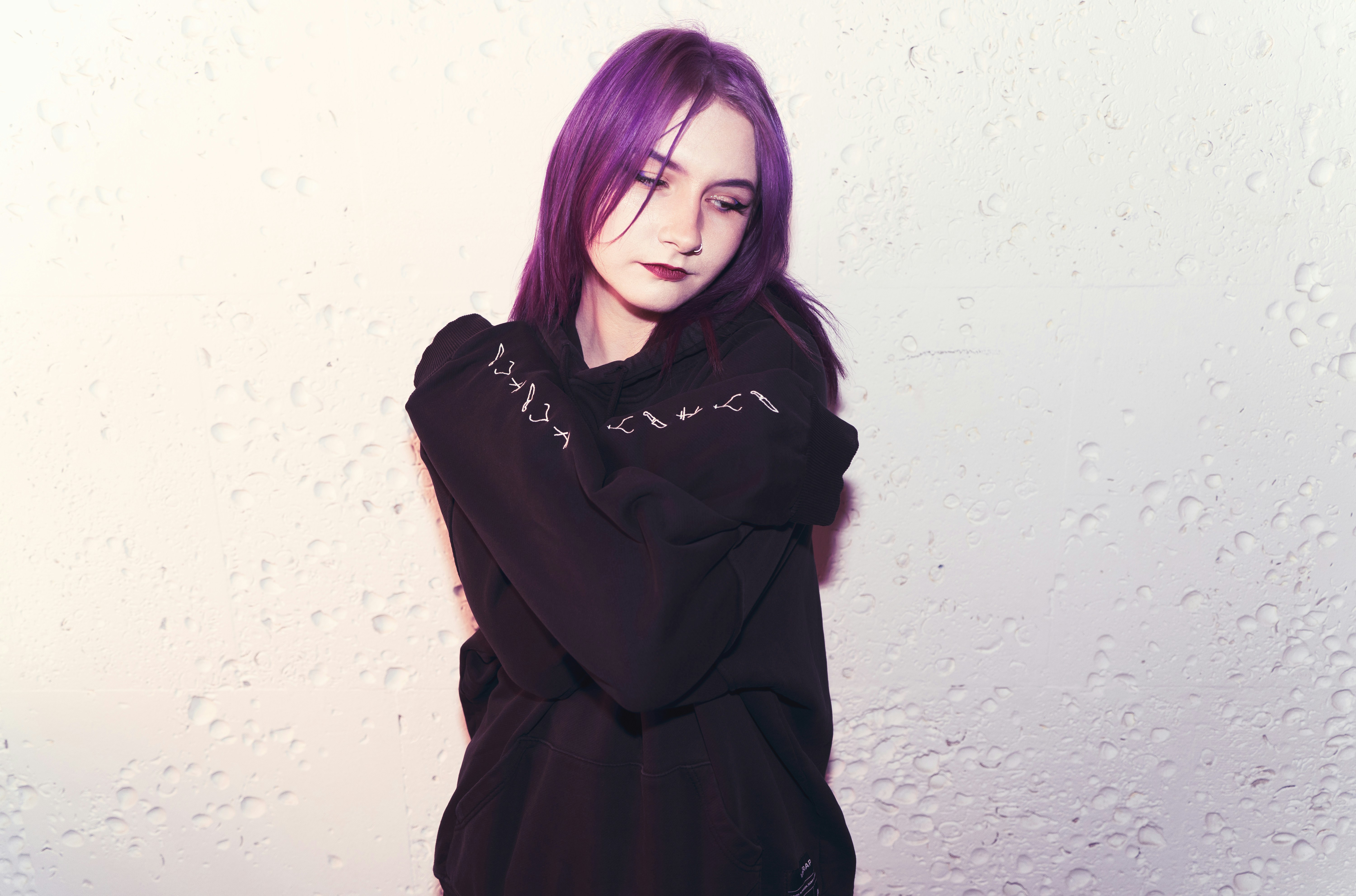 Jeune femme aux cheveux violets portant un sweat à capuche noir