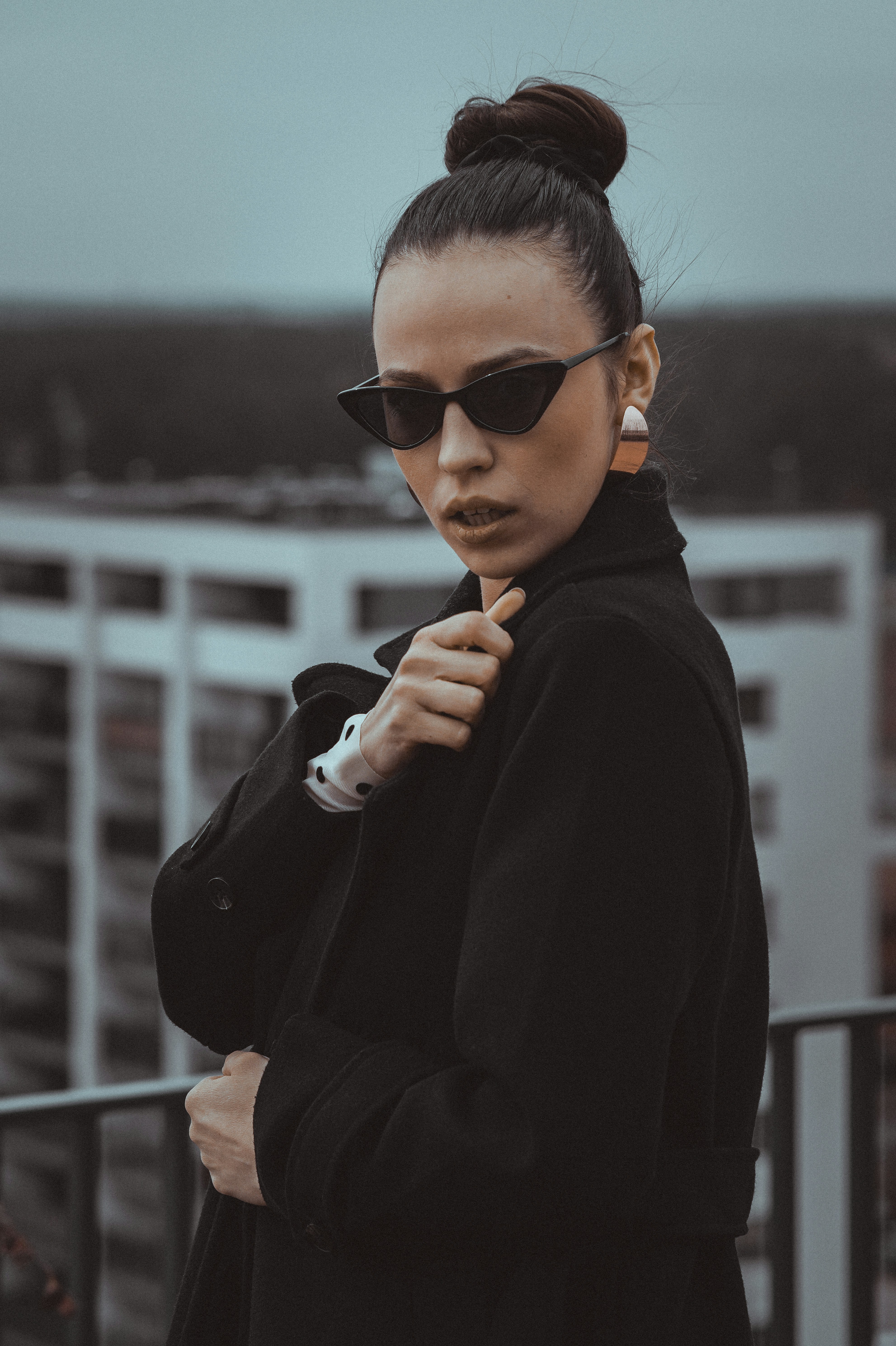 Wanita berkacamata hitam dan mantel hitam di luar ruangan