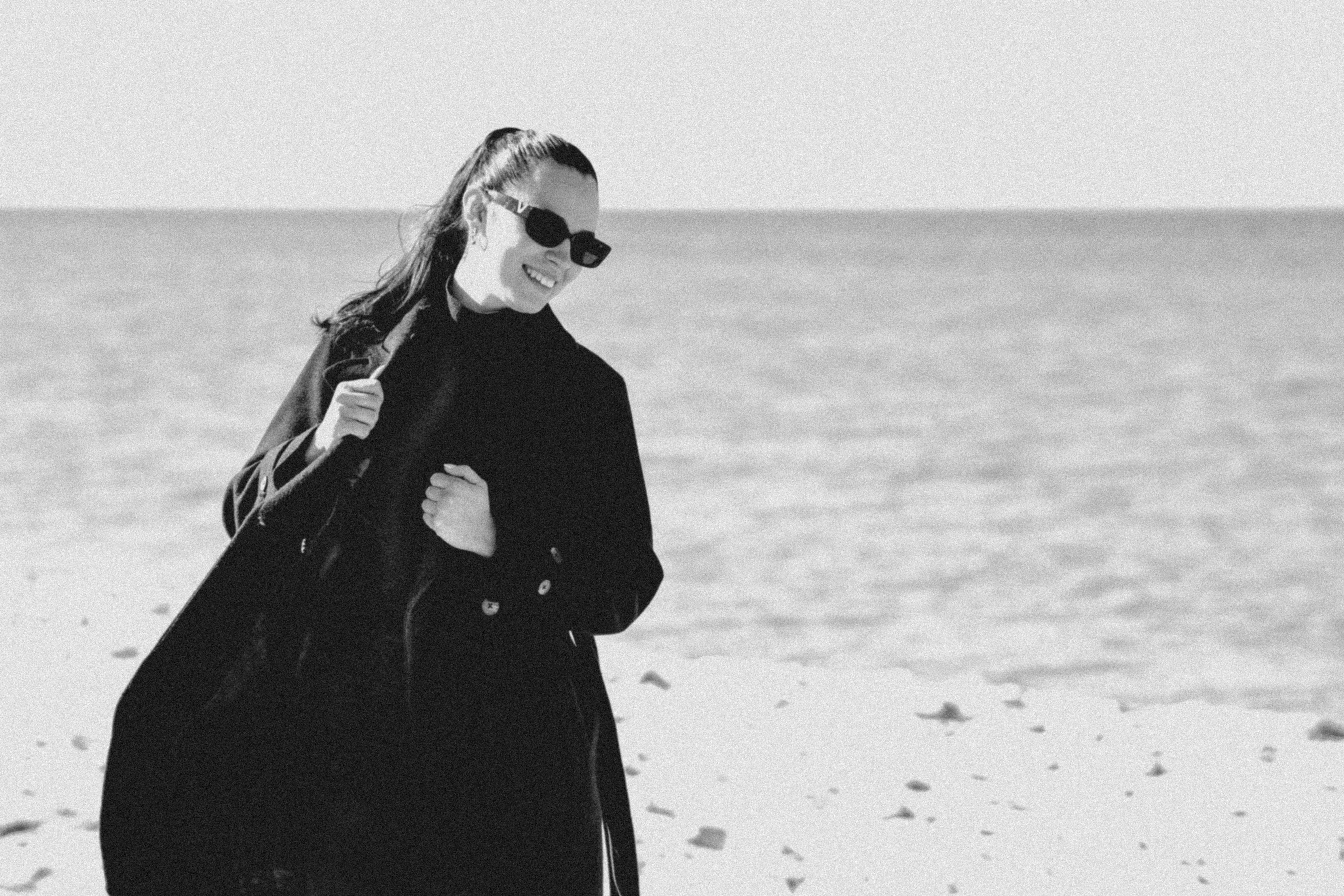 Wanita bermantel hitam di pantai