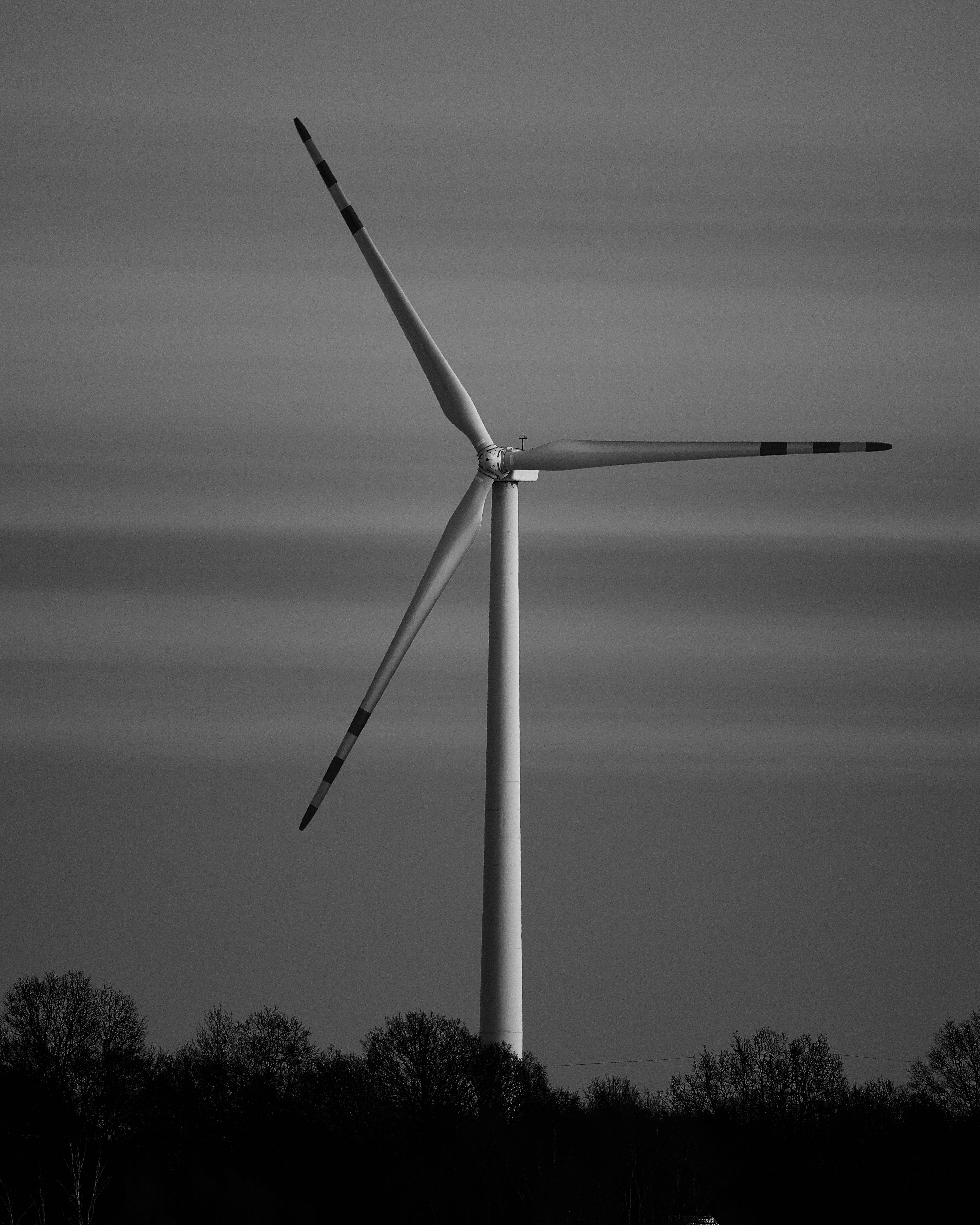 A lone wind turbine stands against a cloudy sky.