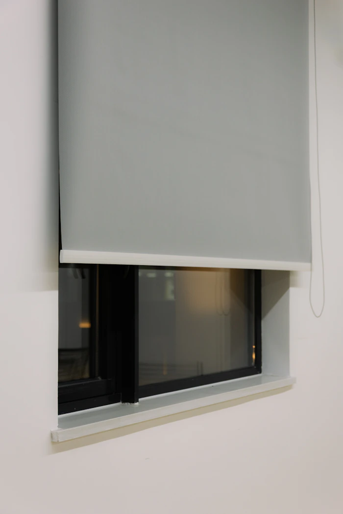 Gray roller shade partially lowered on a modern window in a clean interior